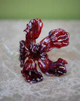 Closeup details of the Alex Rosenbaum Red Glass Flower on green background.
