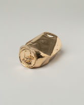 View from the side of the Pearce Objects Cast Bronze Crushed Can on light color background.