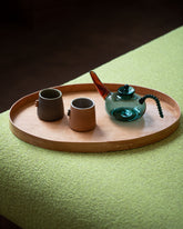 Styled image featuring the Rikke Falkow Large Cherry Wood Serving Tray, with the Ornamental by Lameice Teal & Amber Dreamlike Teapot and Emris Brick Clay and Dark Stoneware Nub Cups.
