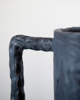 Closeup details of the Giselle Hicks Coal Black Cylinder Vessel with Square Handle on light color background.
