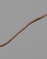 Closeup details of the Pink Seed Pearl Anklet on light color background.