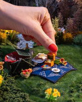 Styled image of the Daffodil Charm, with the California Poppy Charm, Luna Ring Charm, Stick of Salted Butter Charm, Sardine Can Charm, Sardine Fish Charm, Saltine Charm and Caviar Charm.