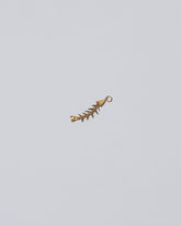 Closeup details of the Skeletal Fish Charm on light color background.