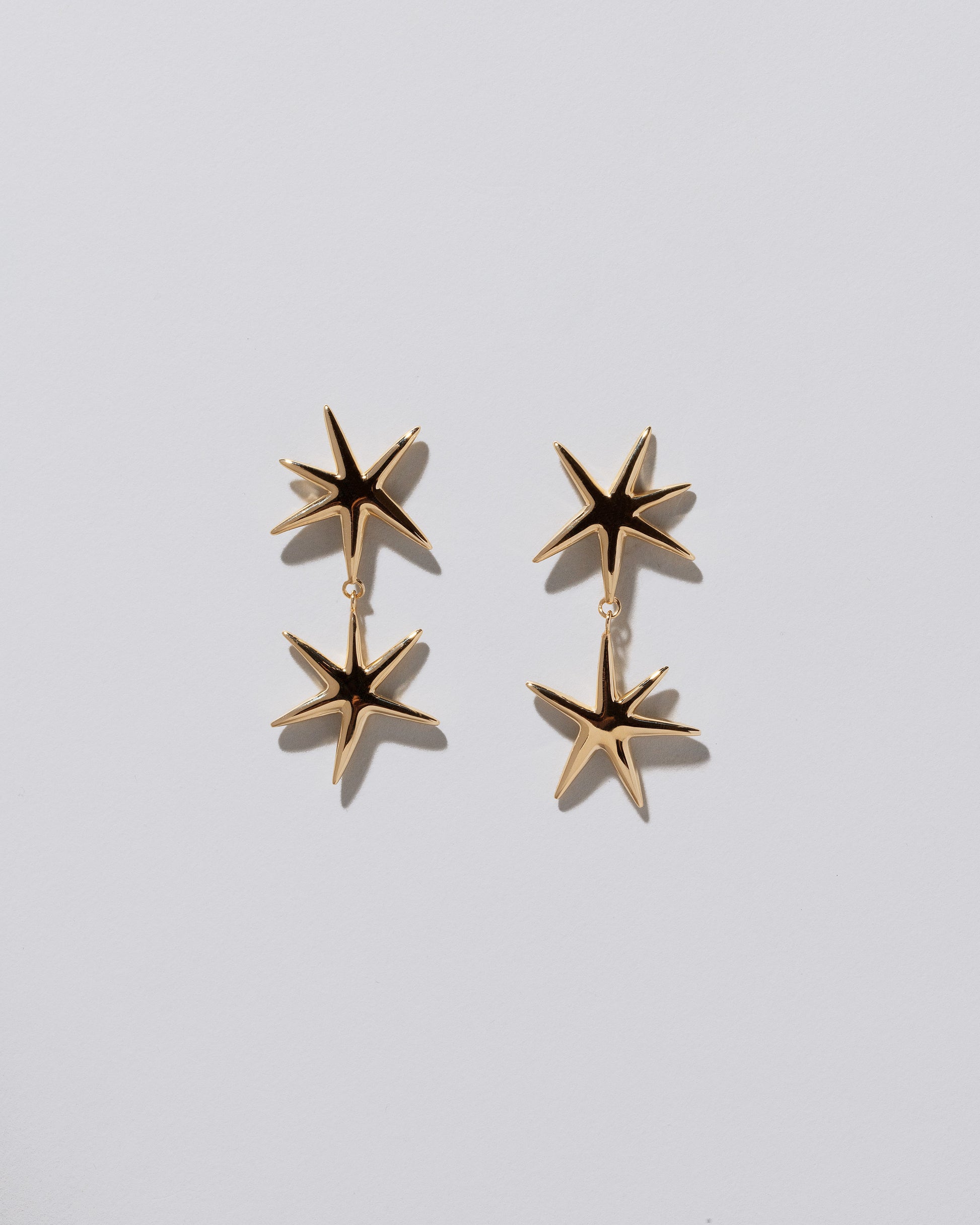 Verve Star Drop Earrings on light color background.