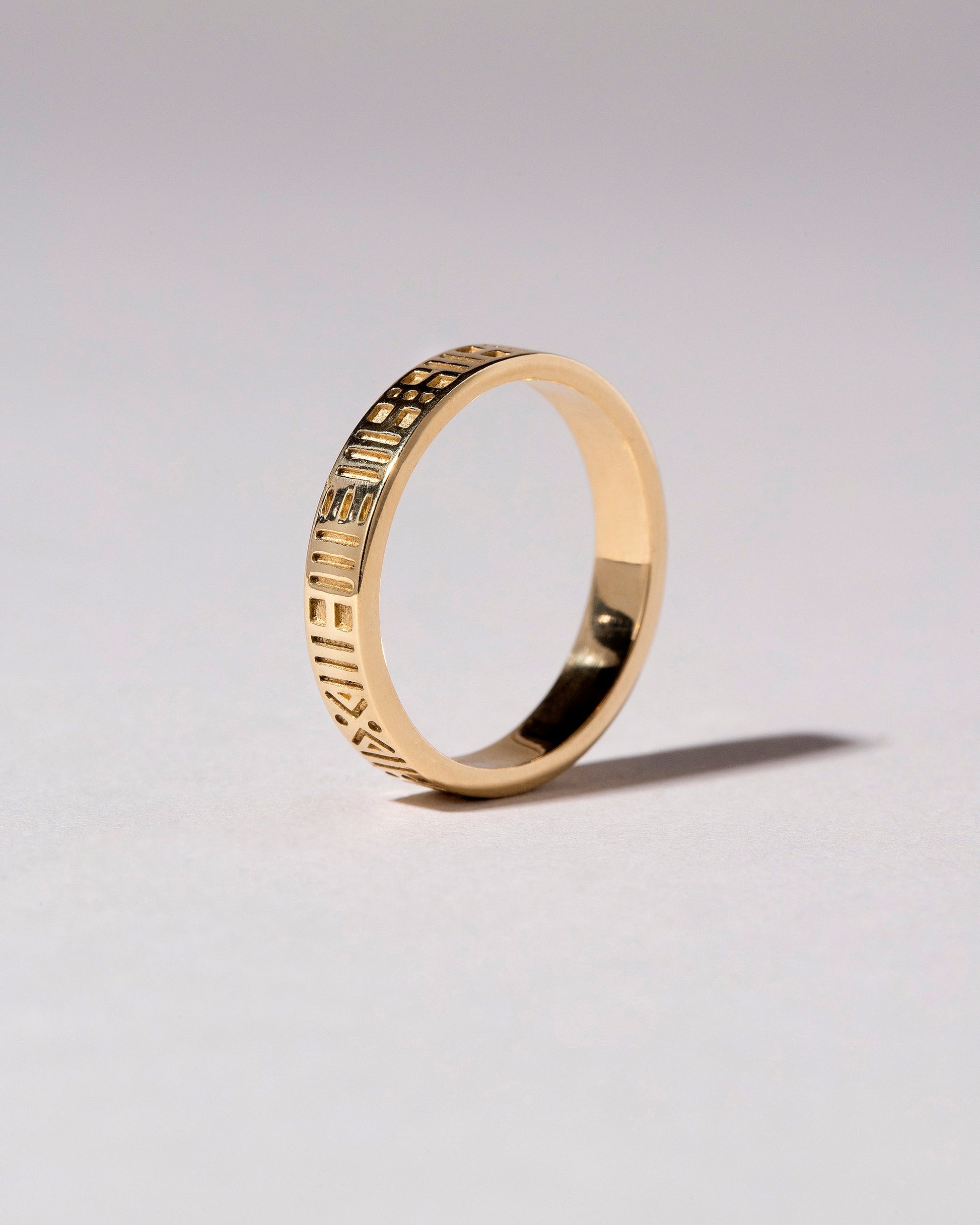 Closeup details of the Gold Infinity Etched Band on light color background.