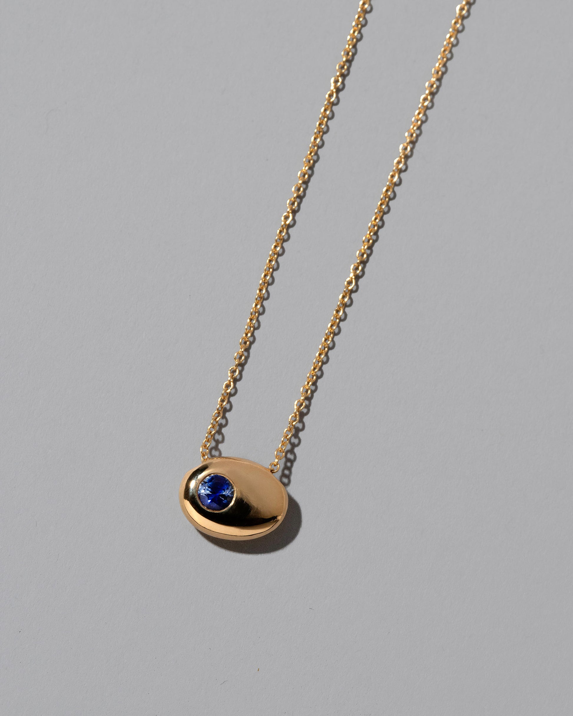 Closeup details of the Gold Bicolor Blue Sapphire Level Necklace on light color background.