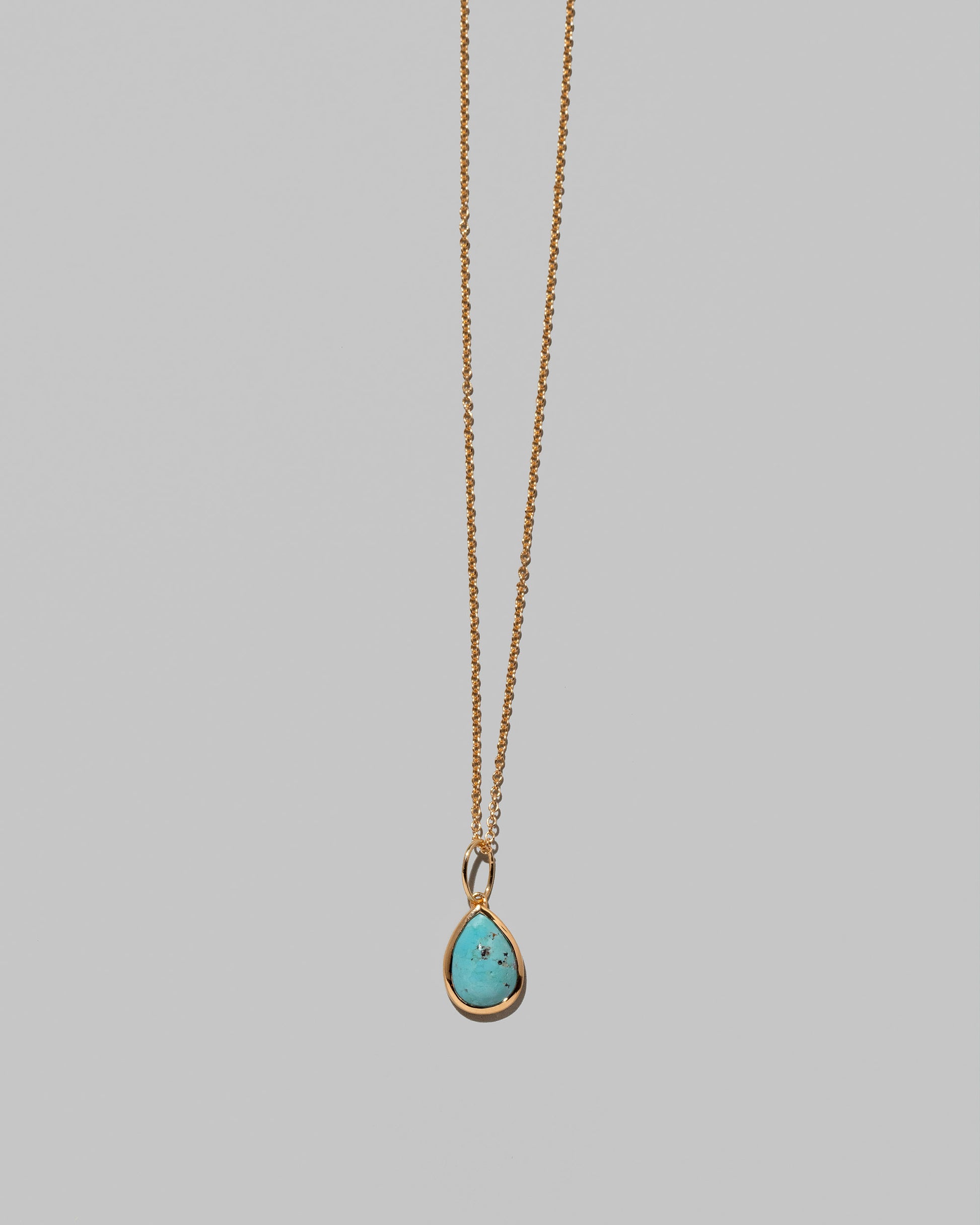 Closeup details of the State Shifter Turquoise Pendant paired with chain on light color background.