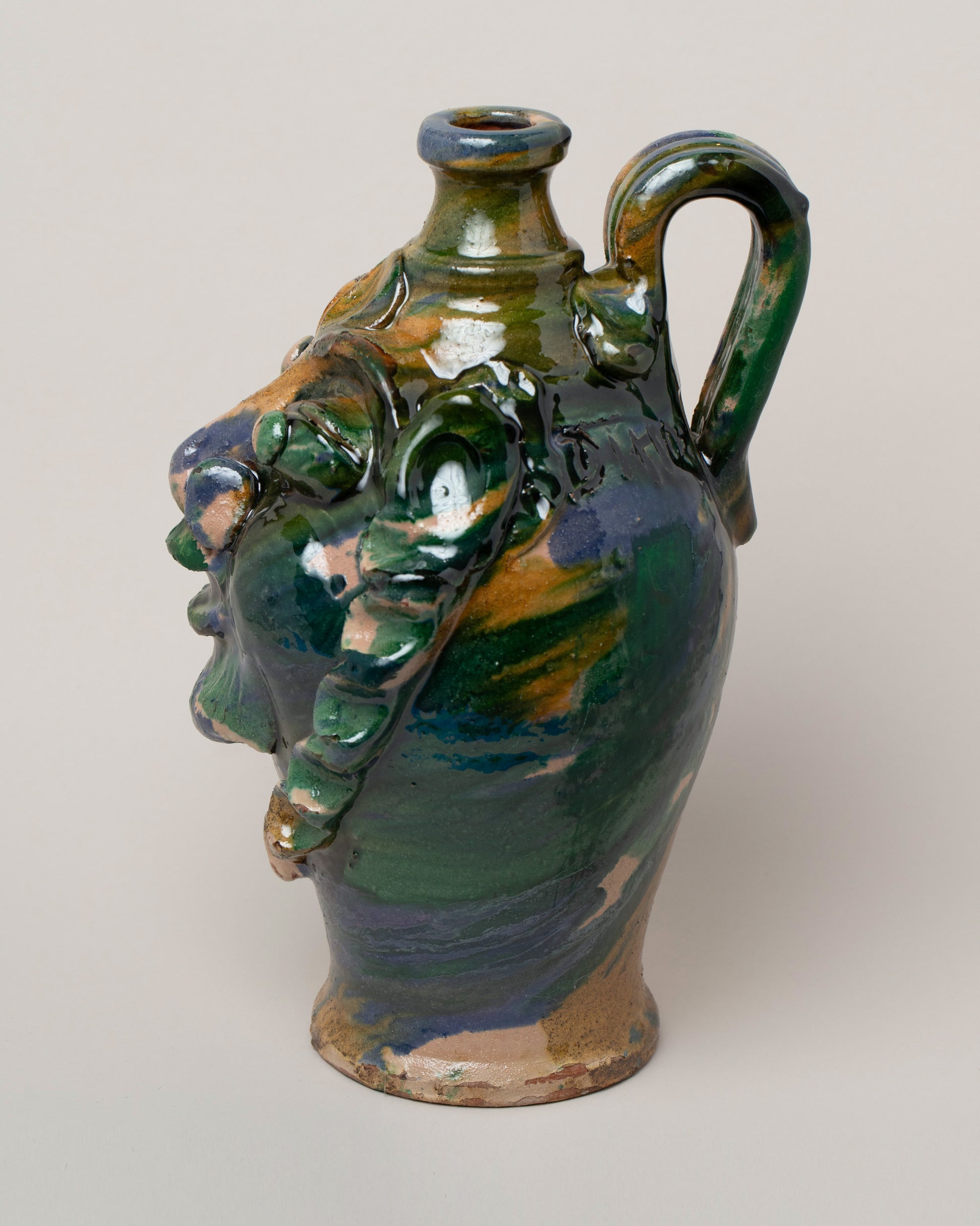 View from the side of the Apotropaia Medium Head Jug Two on light color background.