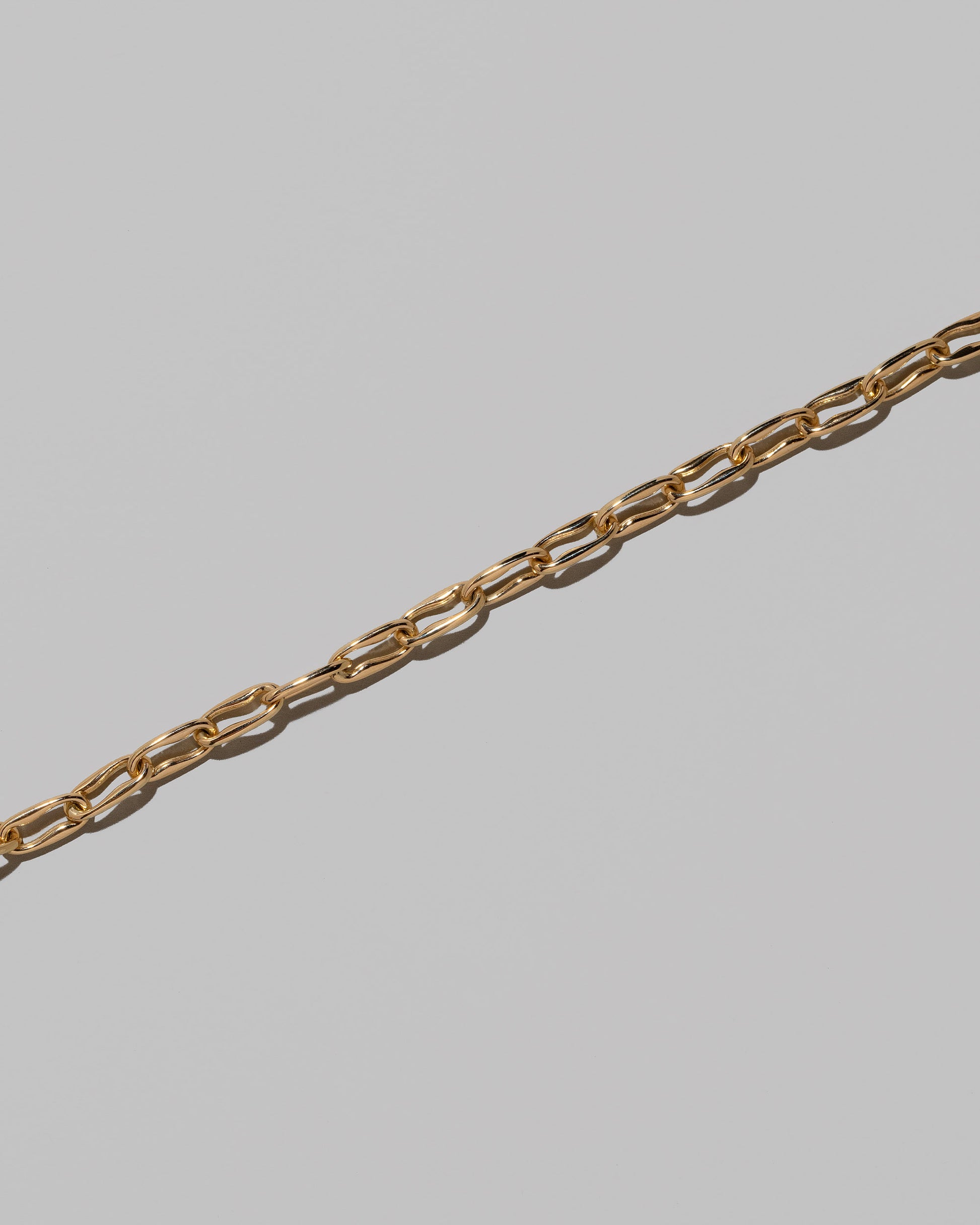 Closeup details of the Wavy Link Chain Necklace on light color background.