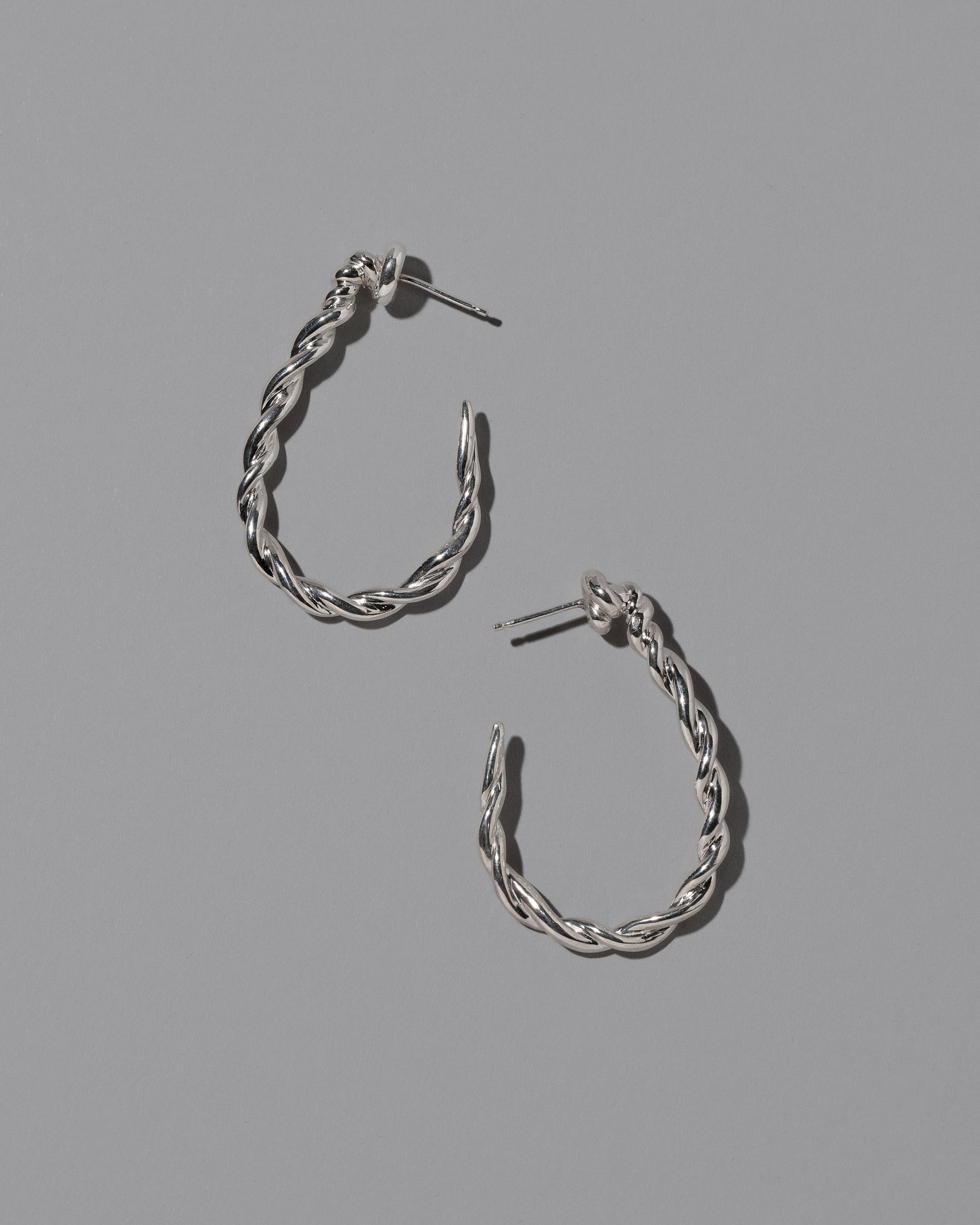 CRZM Sterling Silver Landform Hoop Earrings on light color background.