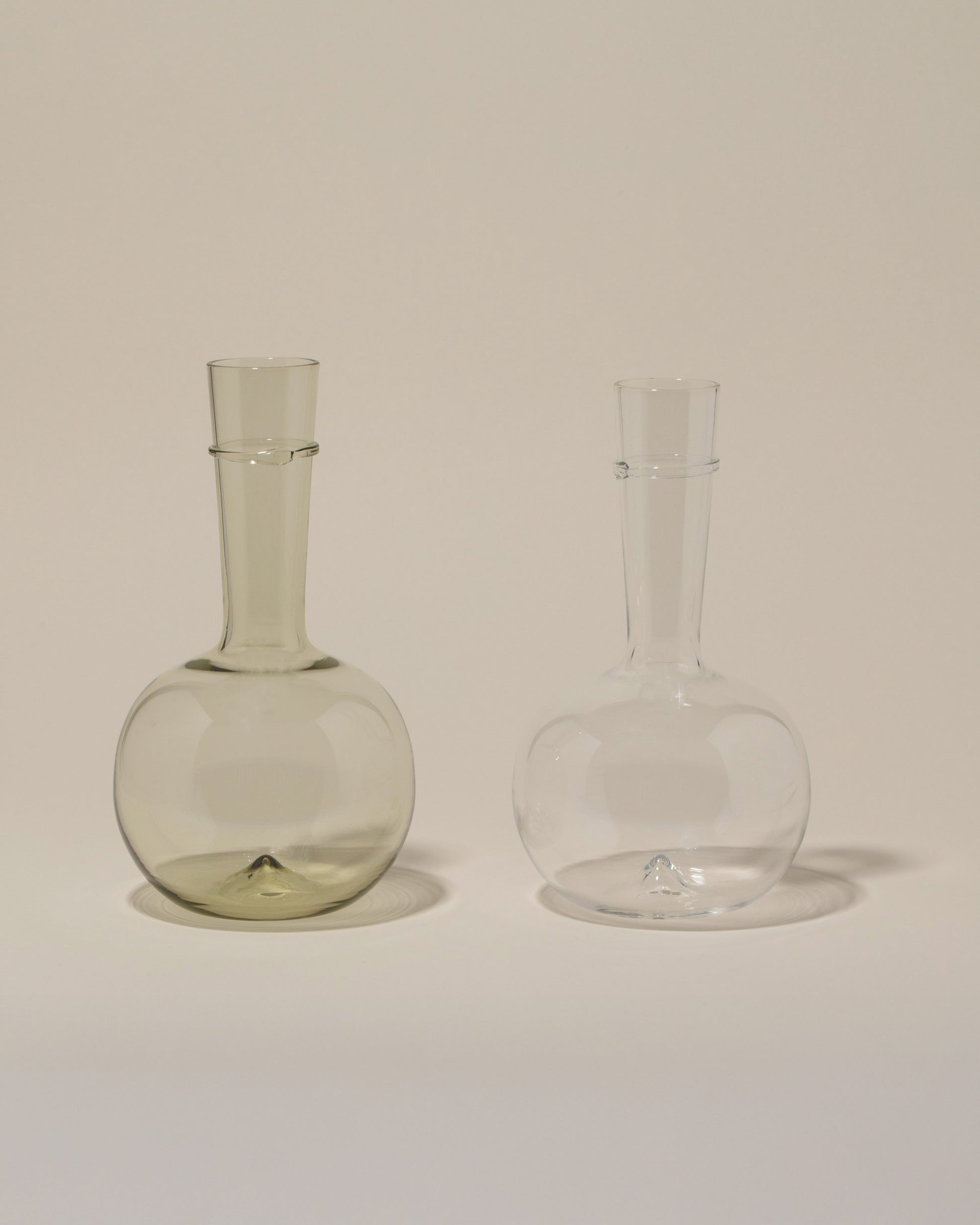 Bollenglass Design Clear Bud Vase and Green Bud Vase on light color background.
