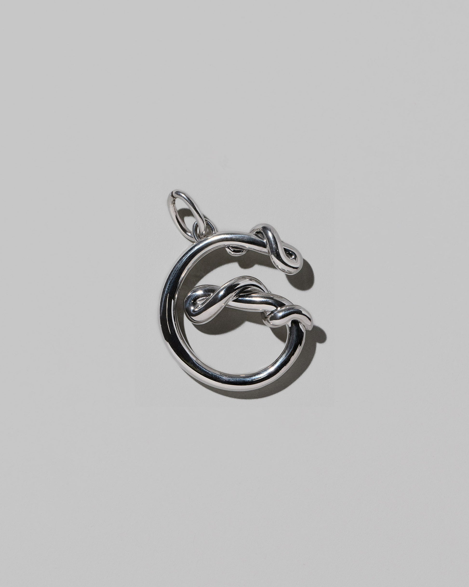 CRZM Sterling Silver Letter G Bag Charm on light color background.