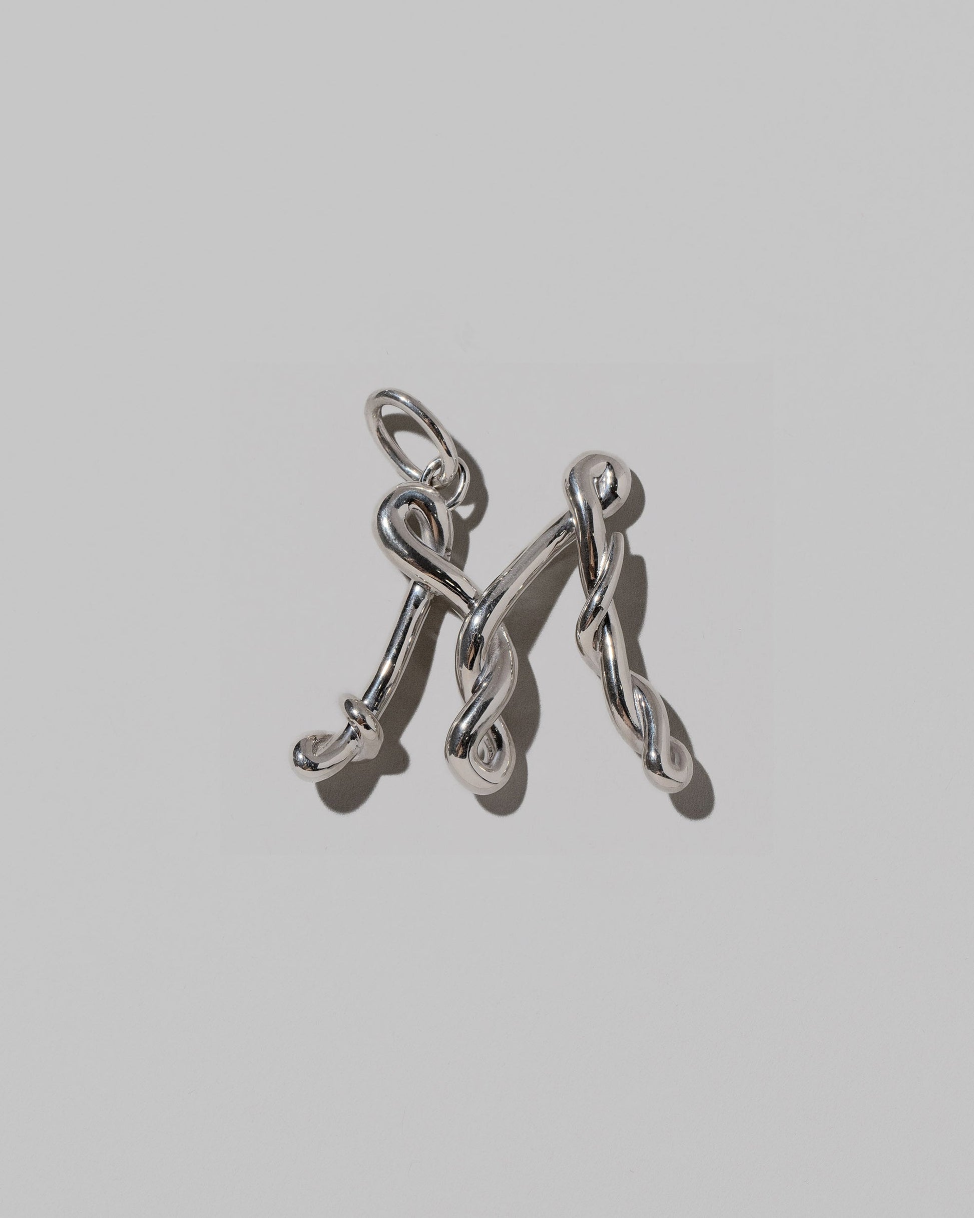 CRZM Sterling Silver Letter M Bag Charm on light color background.