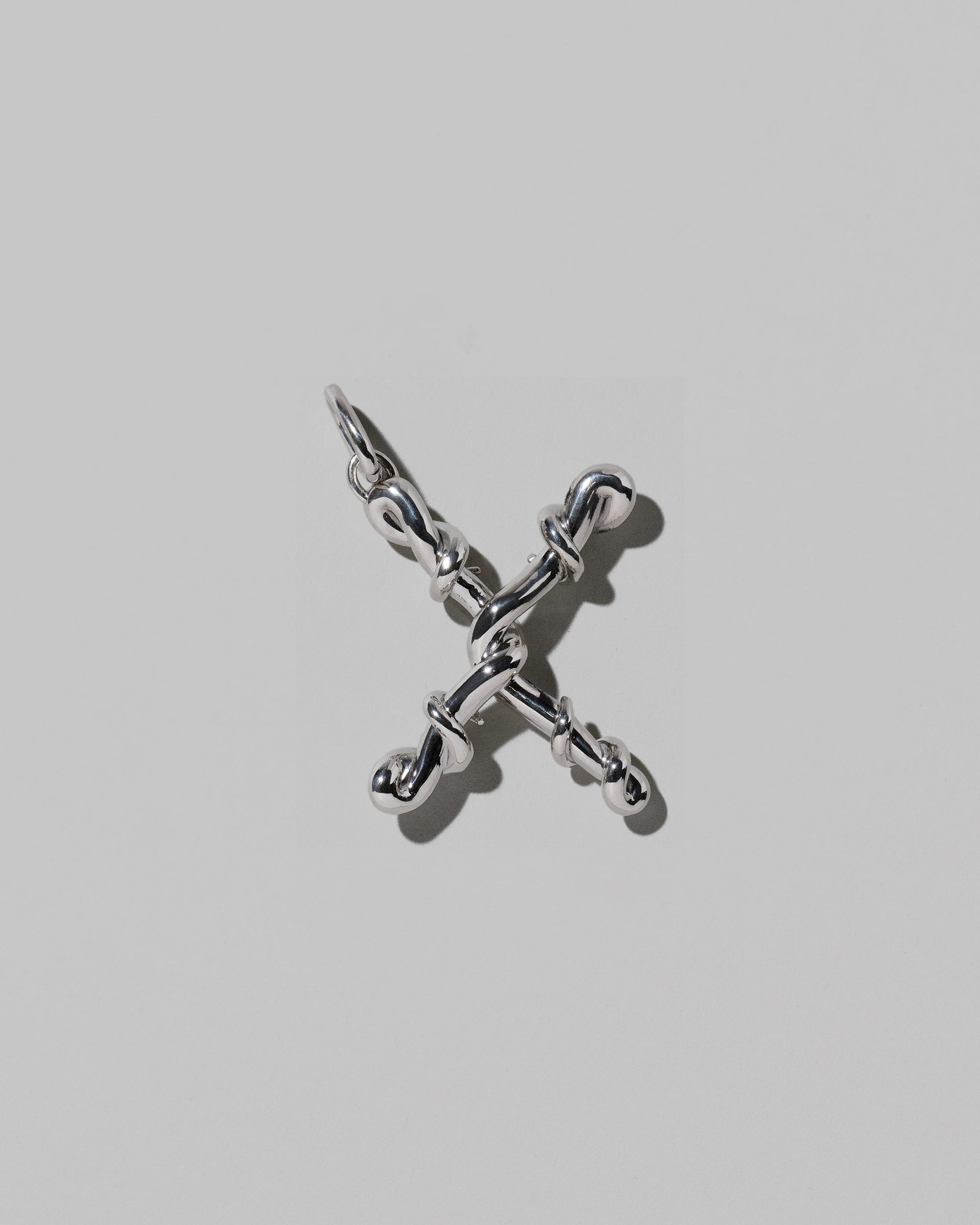 CRZM Sterling Silver Letter X Bag Charm on light color background.