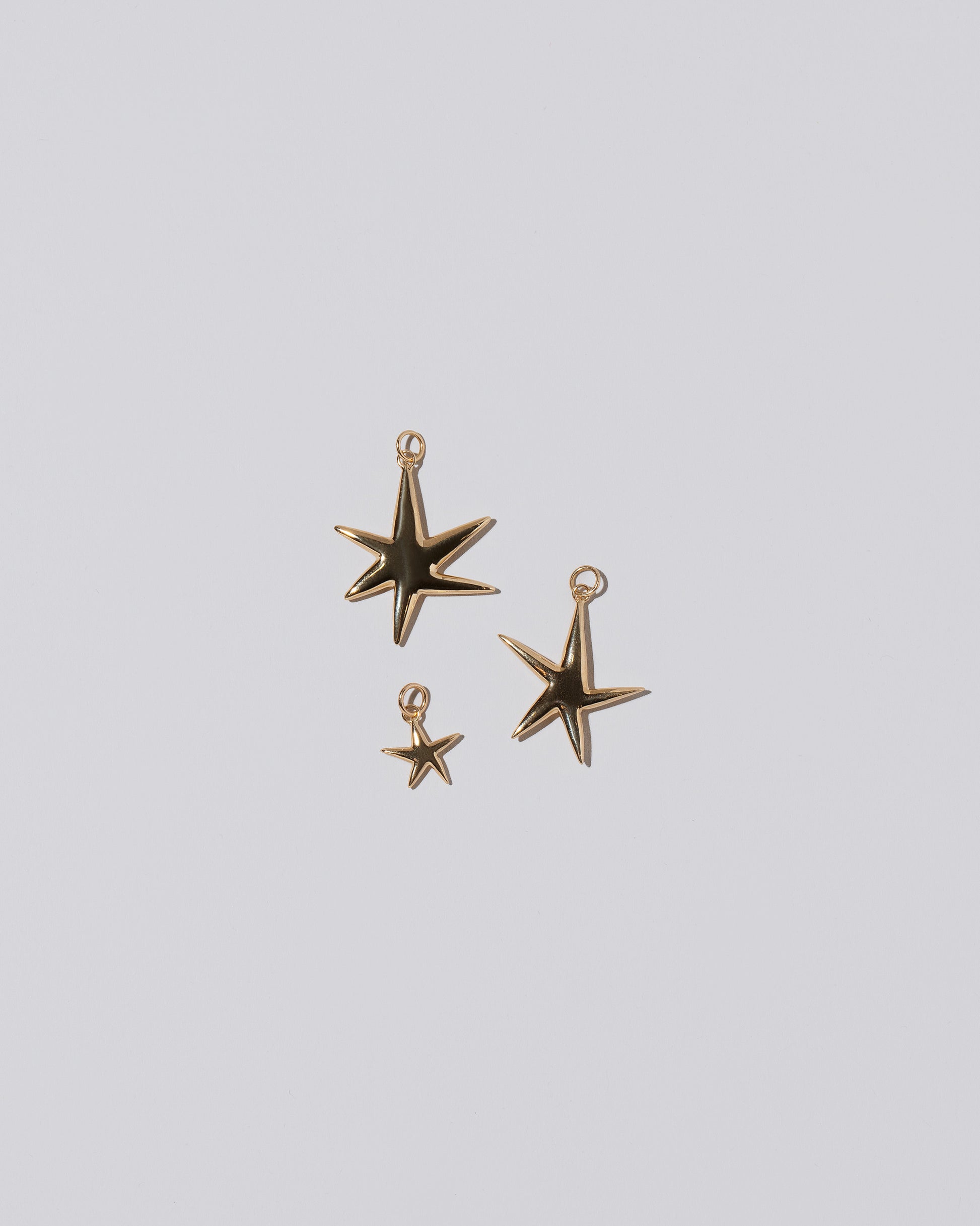 From left to right: A Verve Six Point Star Charms, as well as the small and large Verve Five Point Star Charms on light color background.