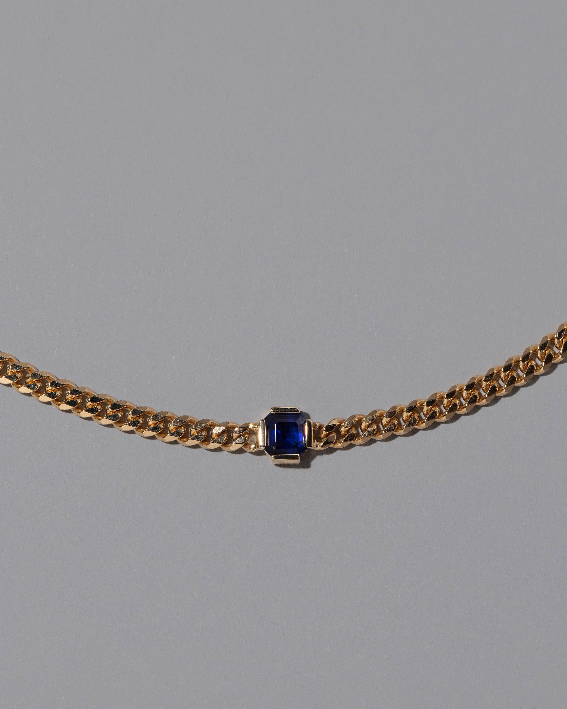 Closeup details of the Blue Sapphire Fold Necklace on grey color background.