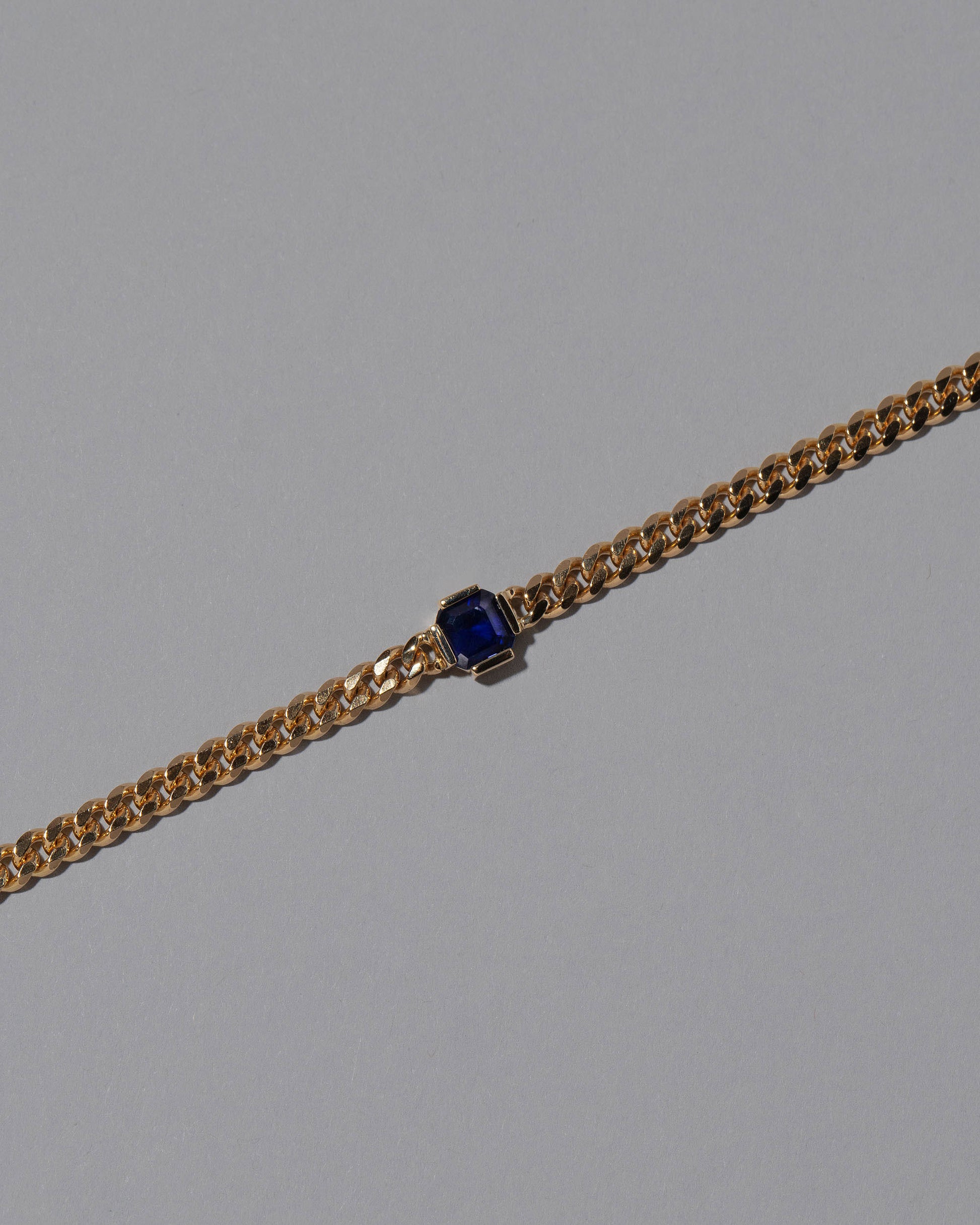 Closeup details of the Gold Blue Sapphire Fold Bracelet on grey color background.