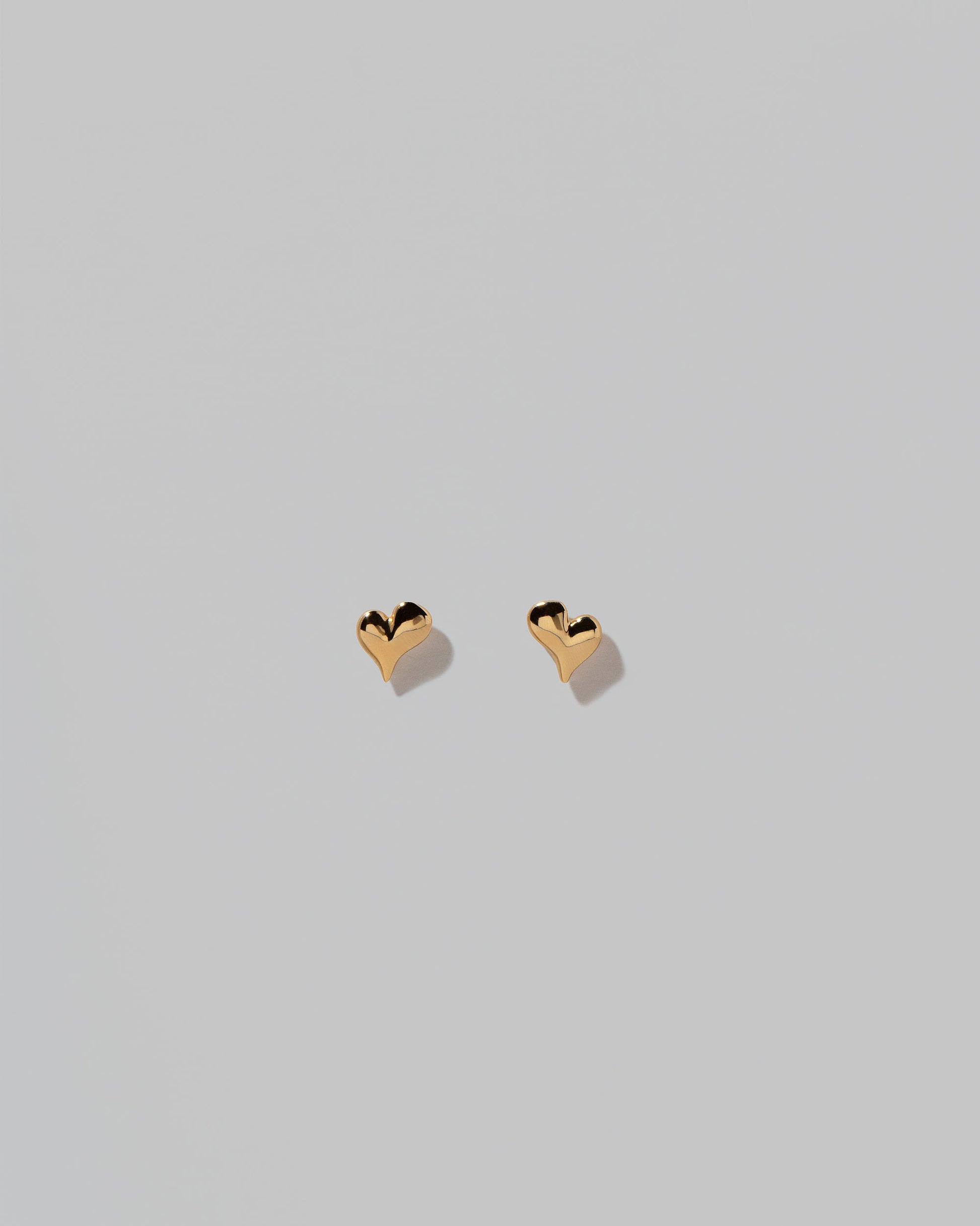 Shape Two Small Thousand & One Night Heart Stud Earrings on light color background.