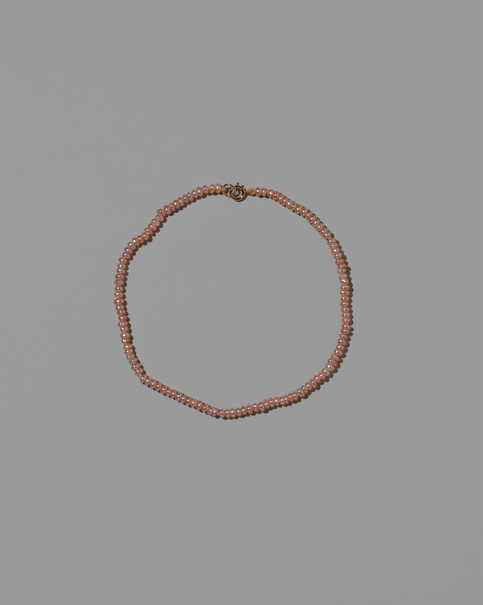 Pink Seed Pearl Anklet on light color background.