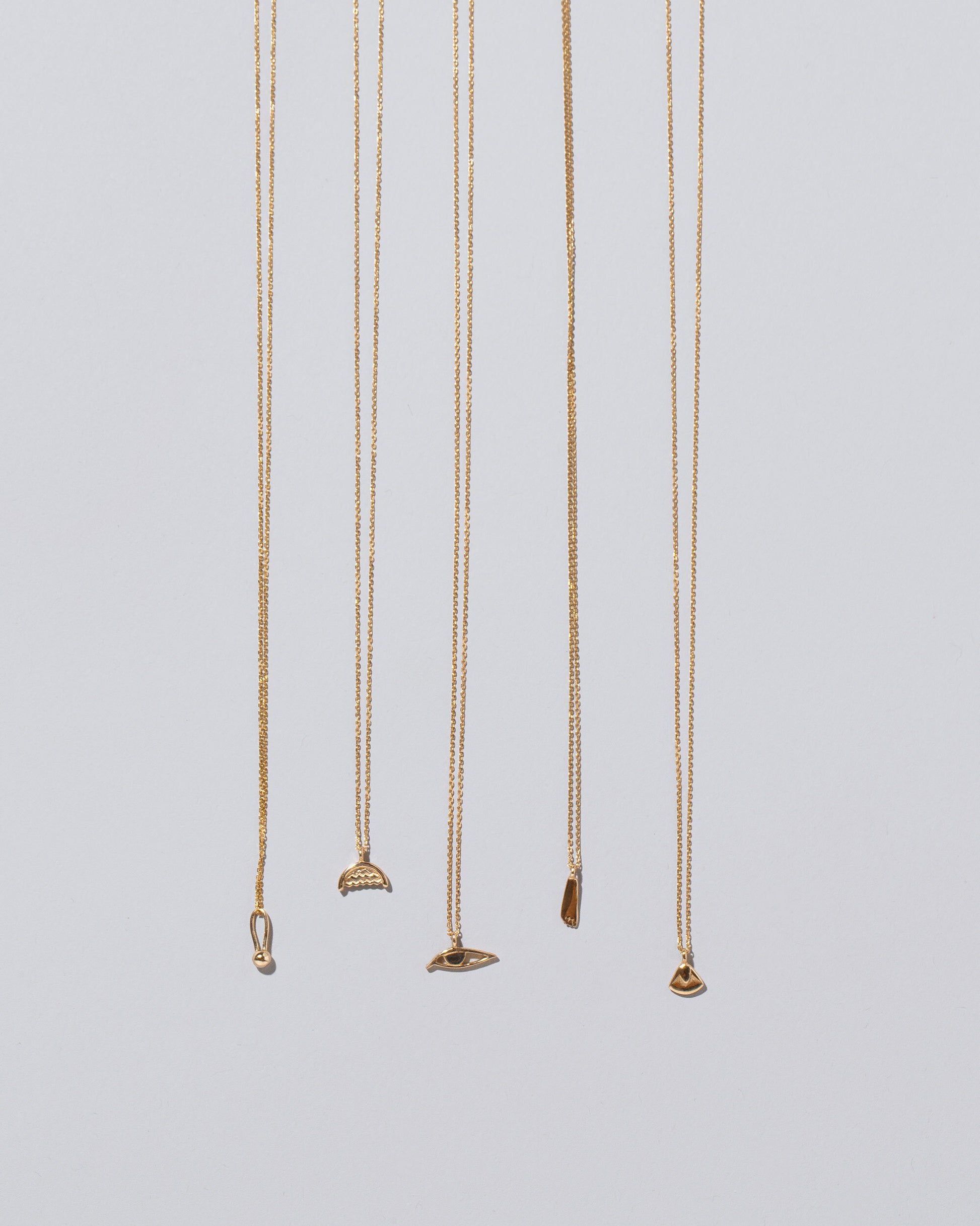 Group of Water, Eye, Foot, Lotus Blossom and Loop & Sphere Talisman Pendant Necklaces on light color background.