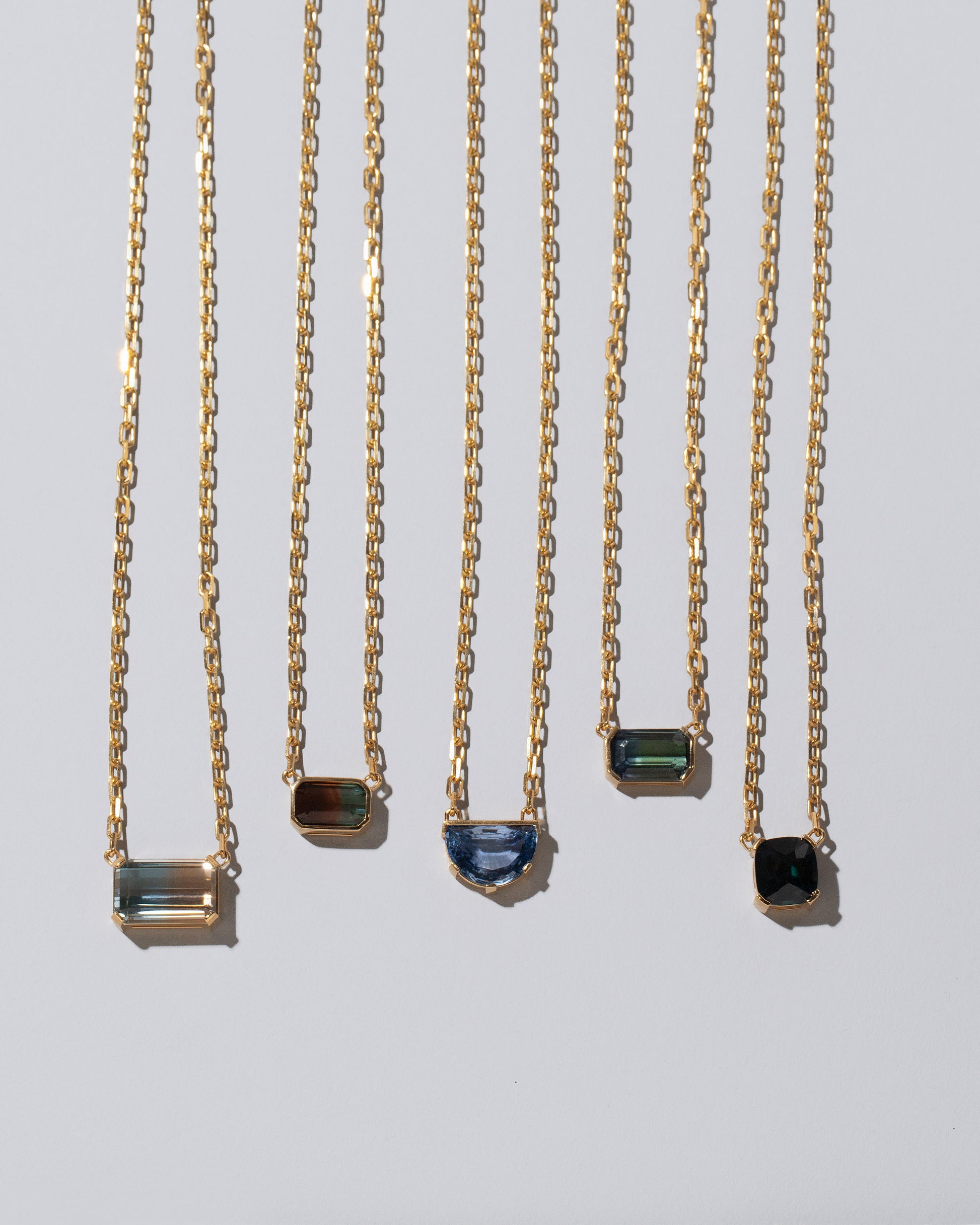 Closeup details of the Highest Path Necklace, Field of Love Necklace, Reverence Necklace, Attunement Necklace and Awareness Necklace on light color background.