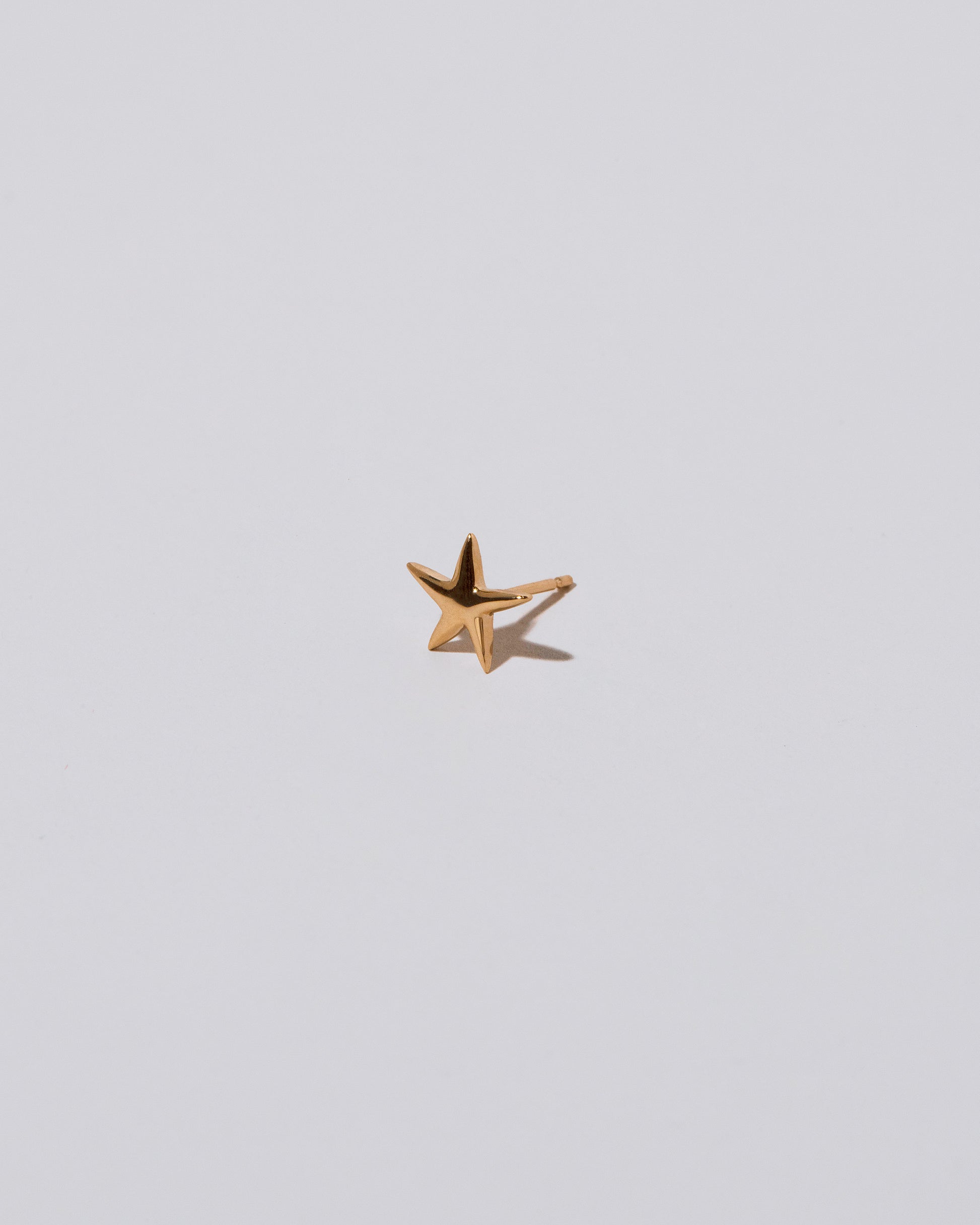 Closeup details of the Shape One Small Verve Five Point Star Stud Earring single on light color background.
