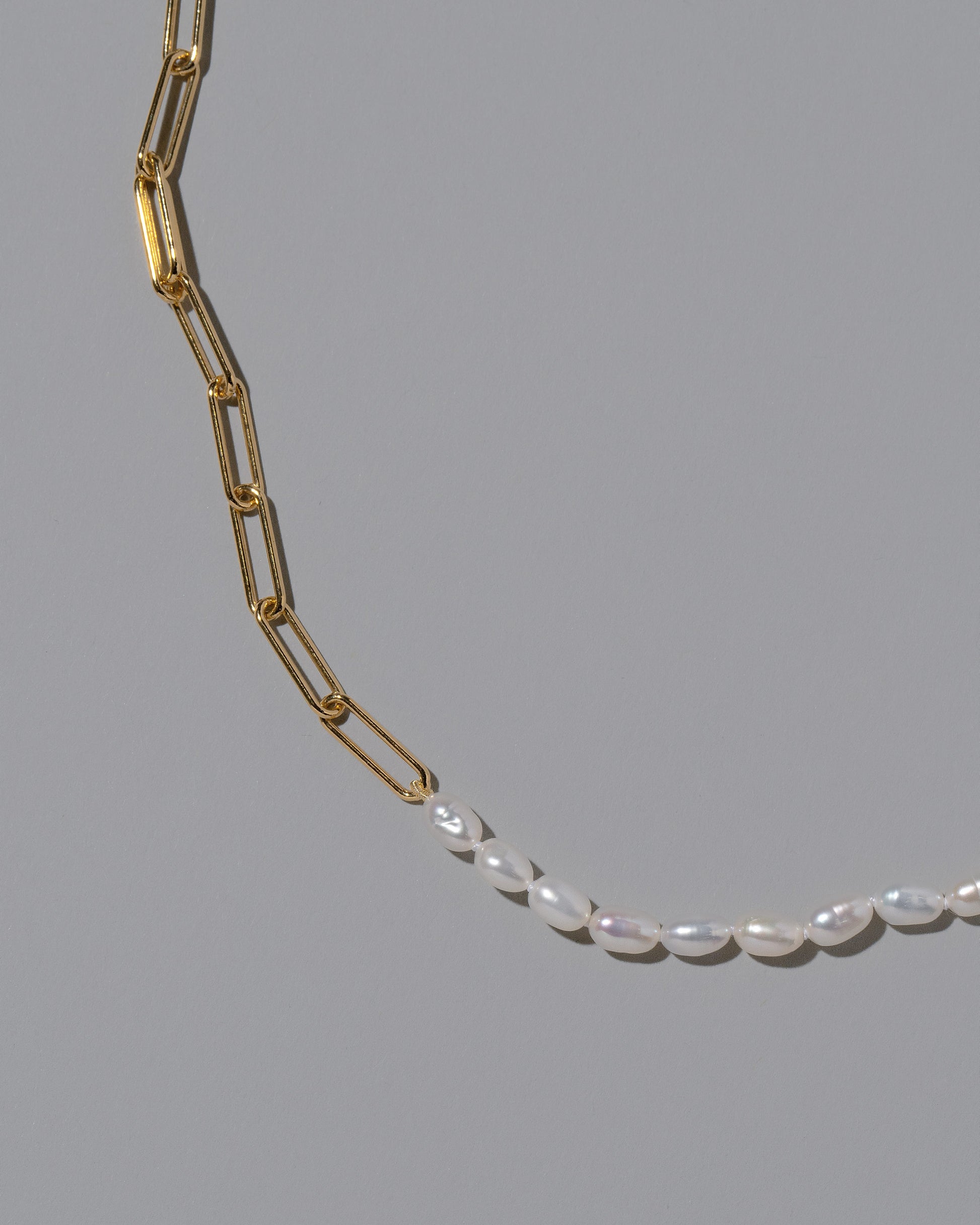 Closeup details of the Rice Pearl Long Oval Necklace on light color background.