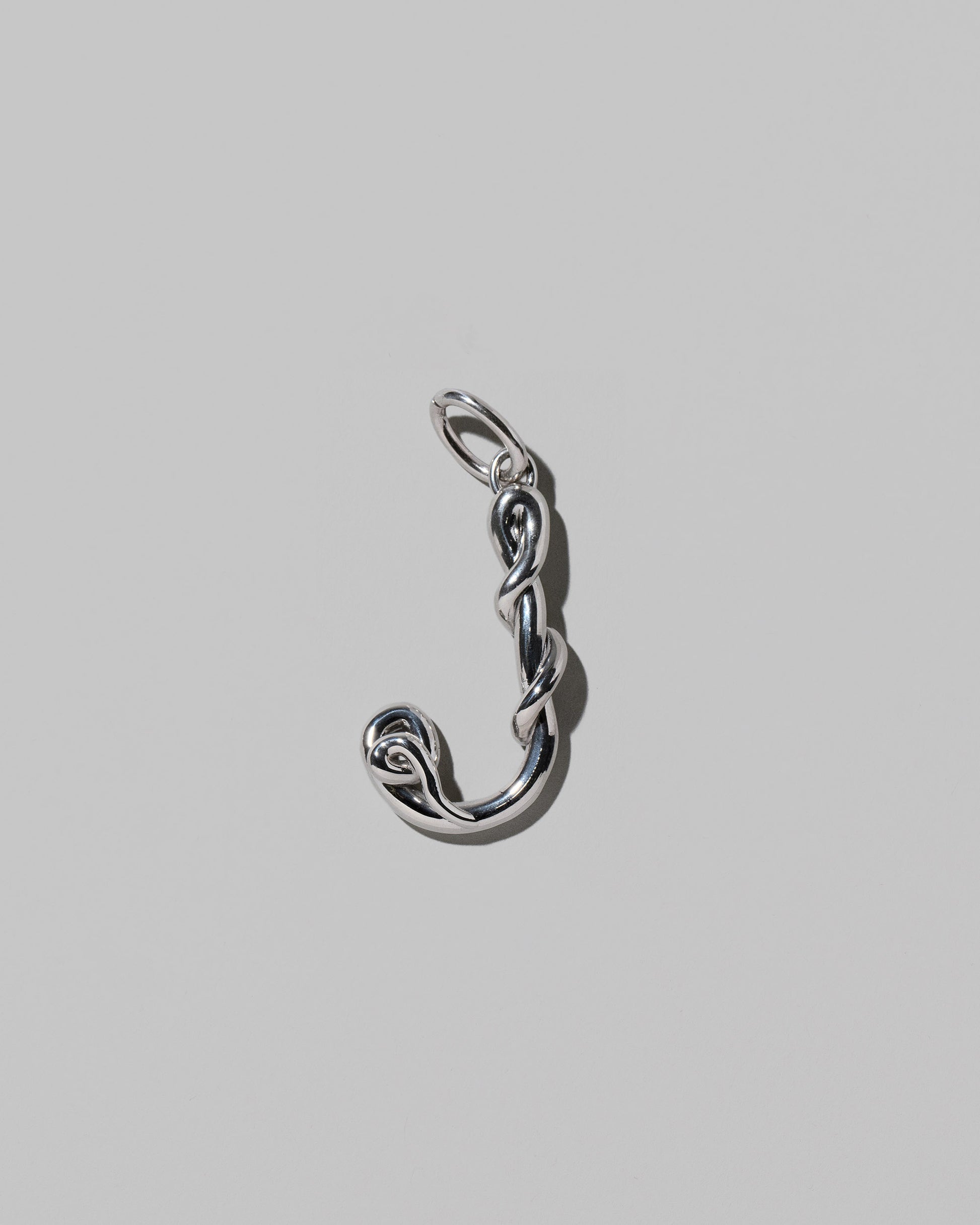 CRZM Large Letter J Charm set in sterling silver on light color background.