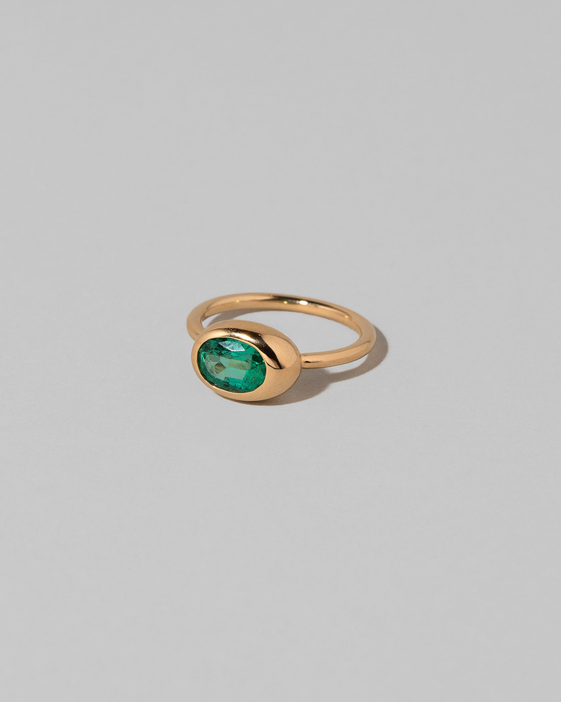 View from the side of the Oval Emerald Equalize Ring on light color background.
