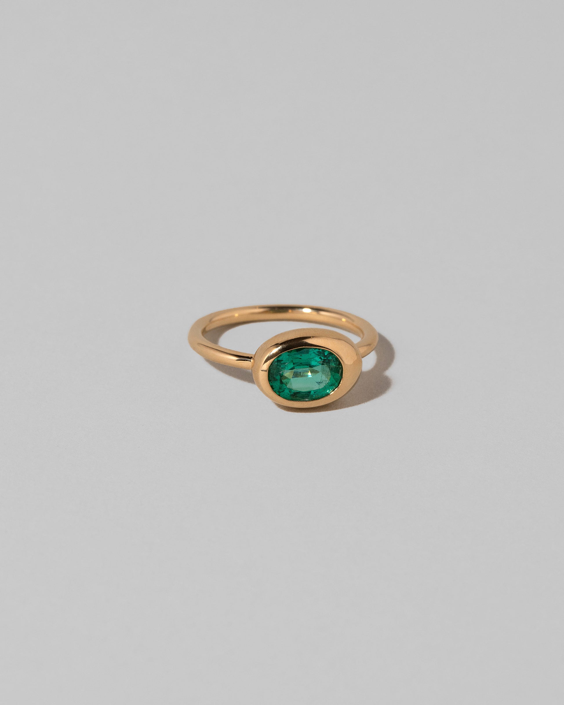 View from the side of the Oval Emerald Equalize Ring on light color background.