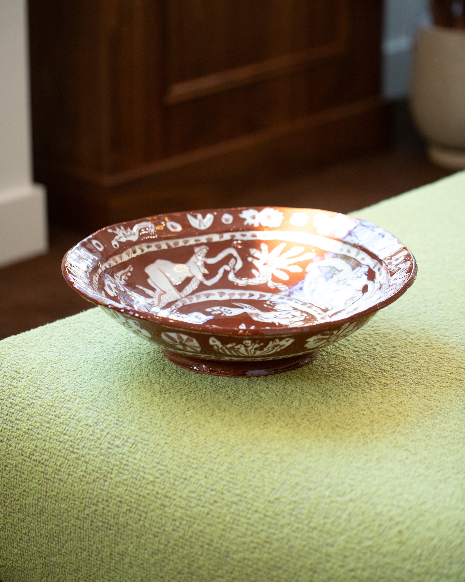 Maggie Boyd Extra Large Chocolate Flower Lickers Bowl on chaise.