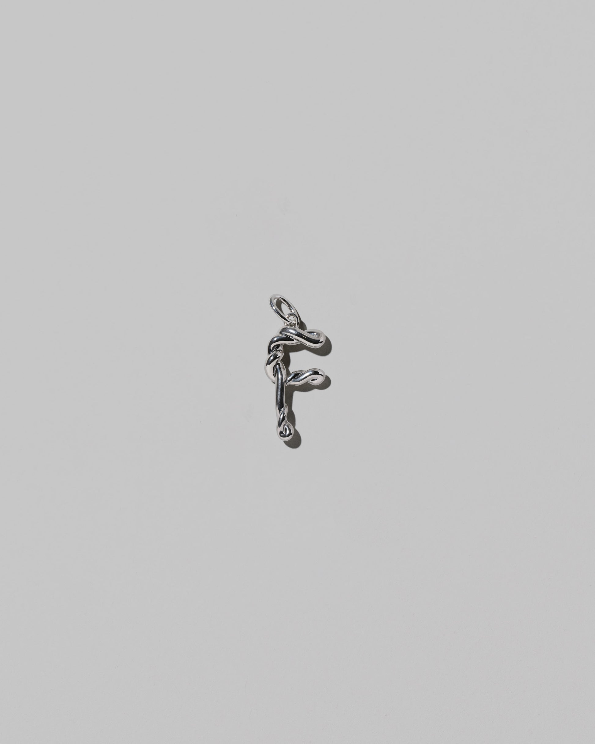 CRZM Medium Letter F Charm set in sterling silver on light color background.