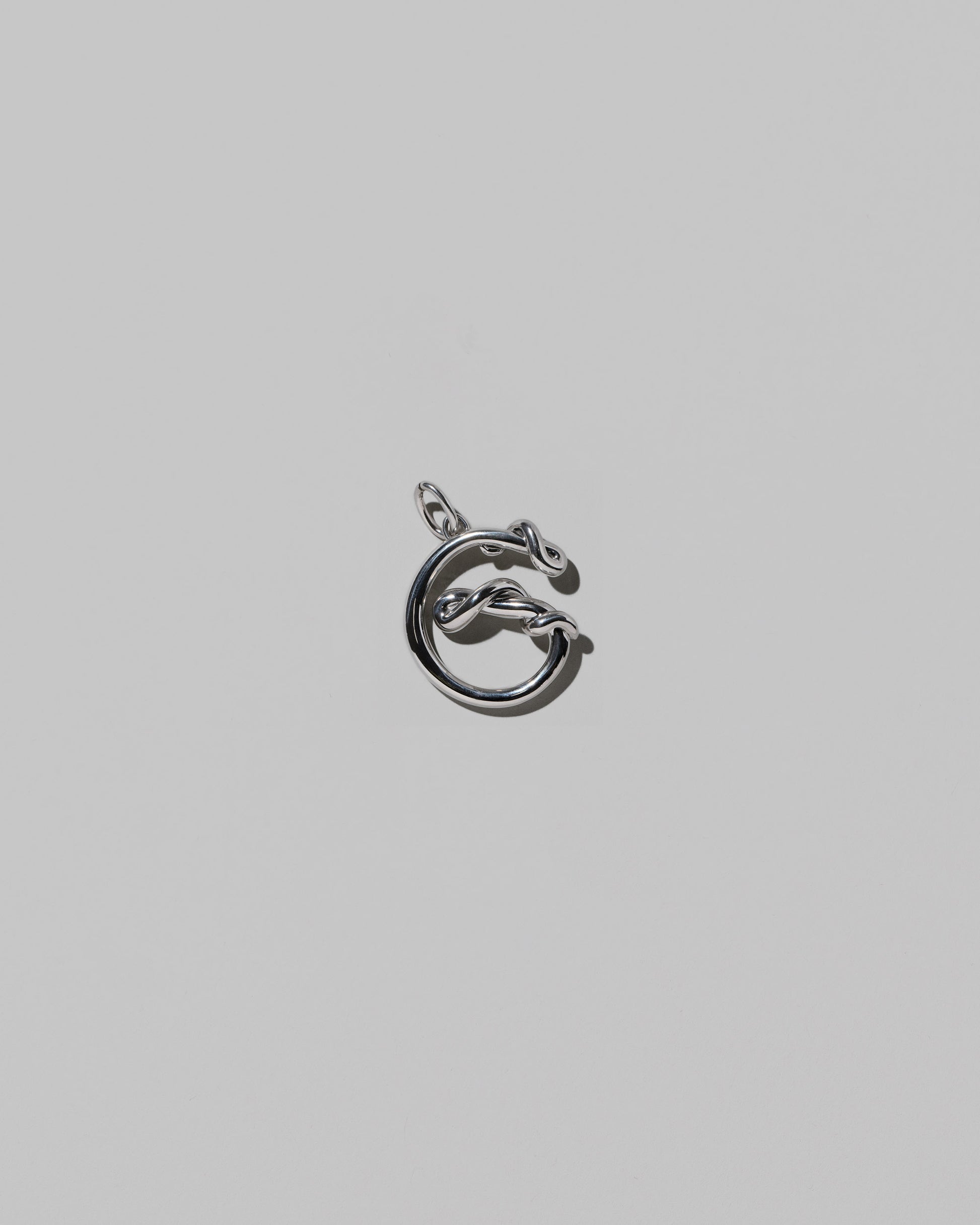 CRZM Medium Letter G Charm set in sterling silver on light color background.