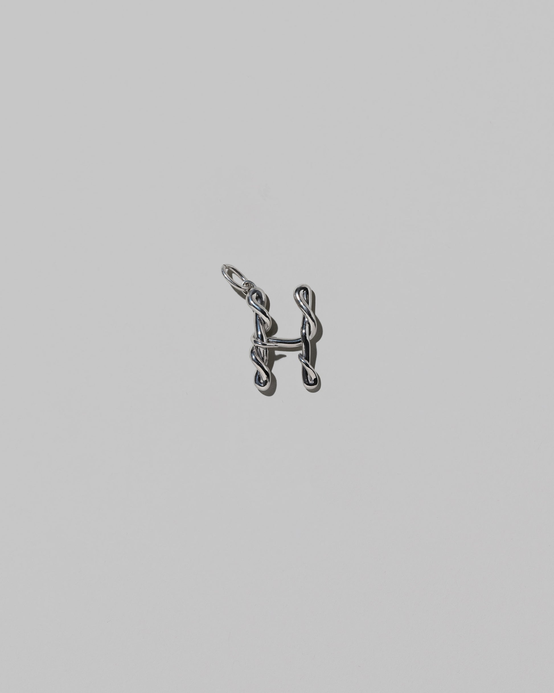 CRZM Medium Letter H Charm set in sterling silver on light color background.