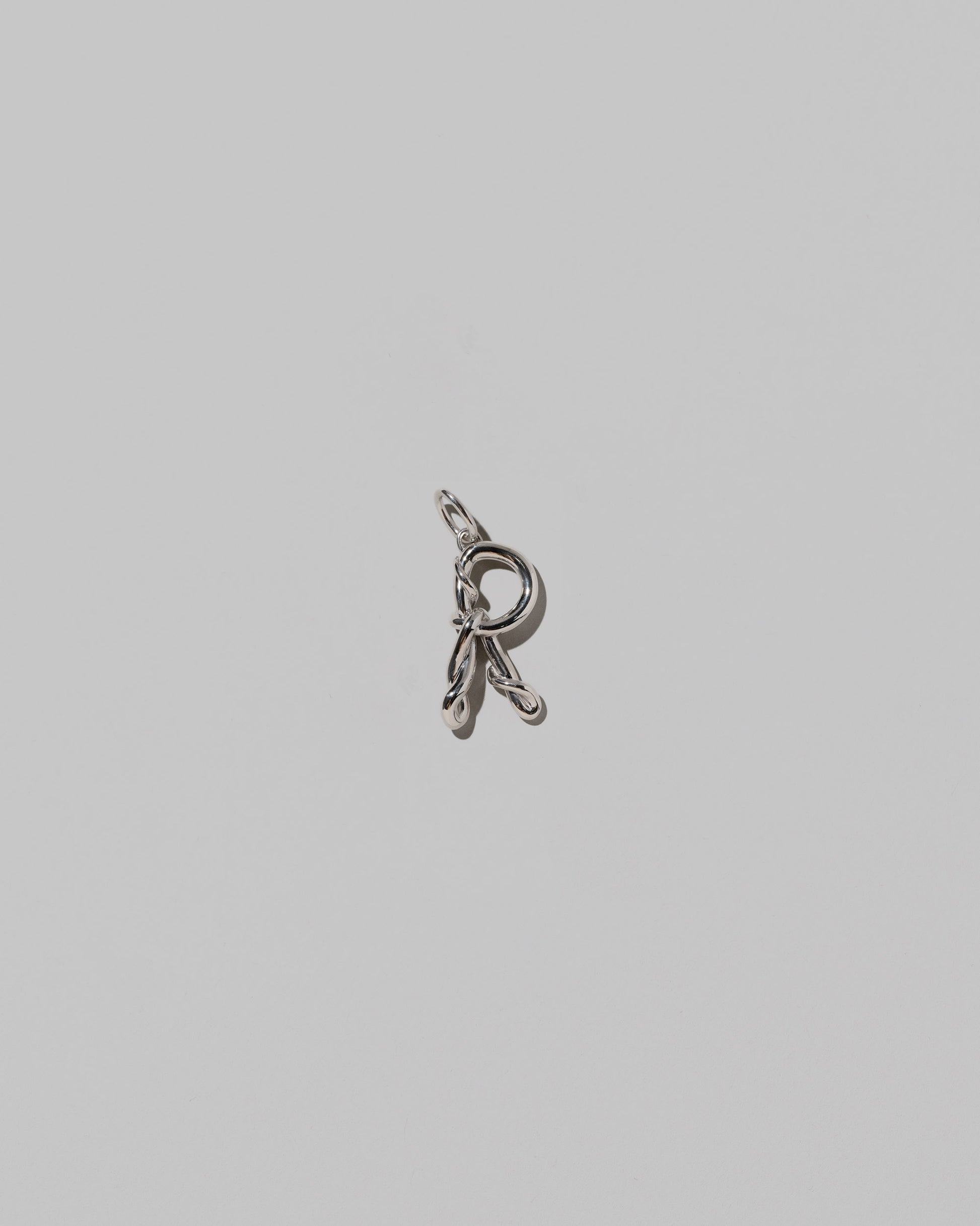 CRZM Medium Letter R Charm set in sterling silver on light color background.