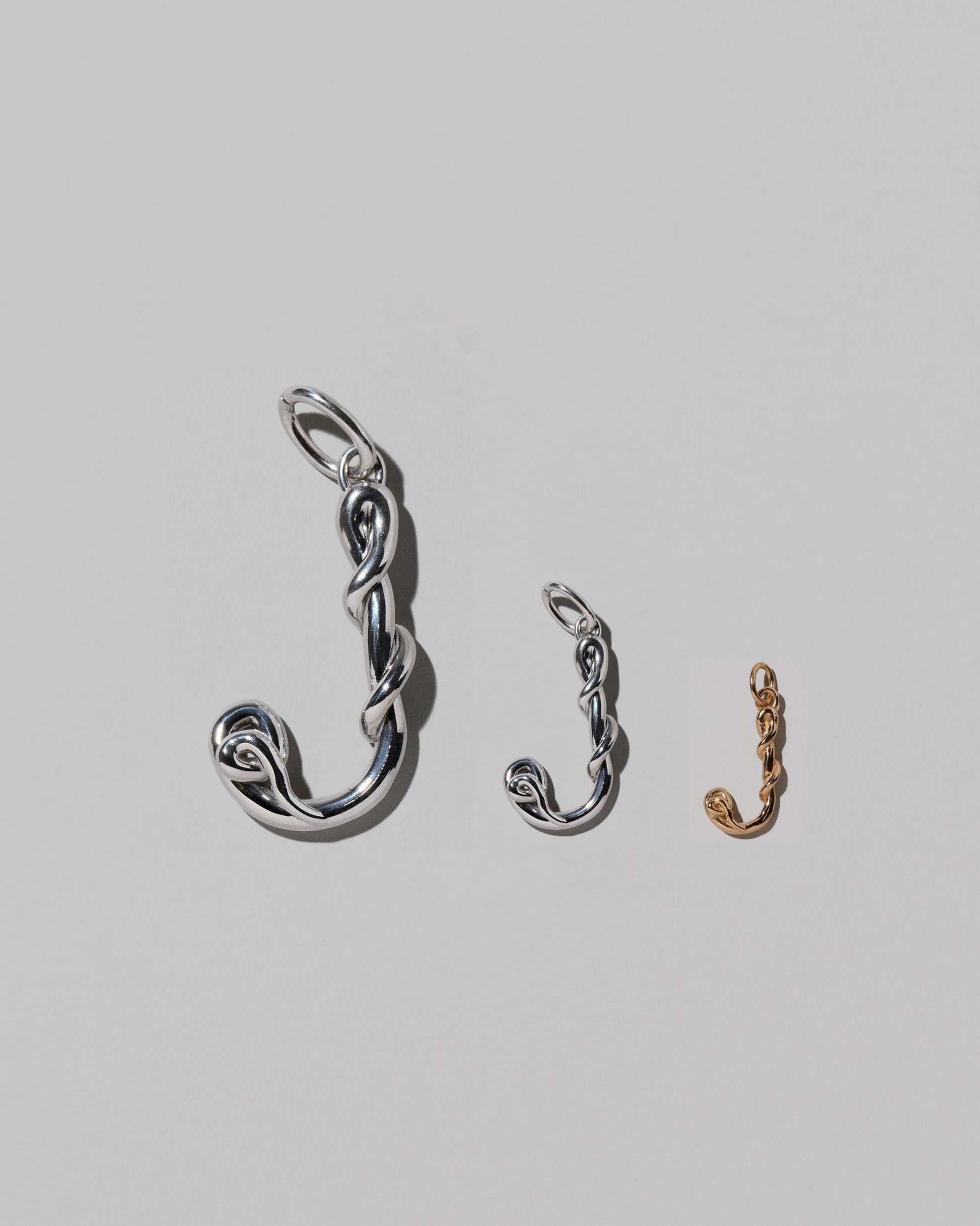 CRZM Large Sterling Silver, Medium Sterling Silver & Mini Letter J Charms set in solid gold on light color background.