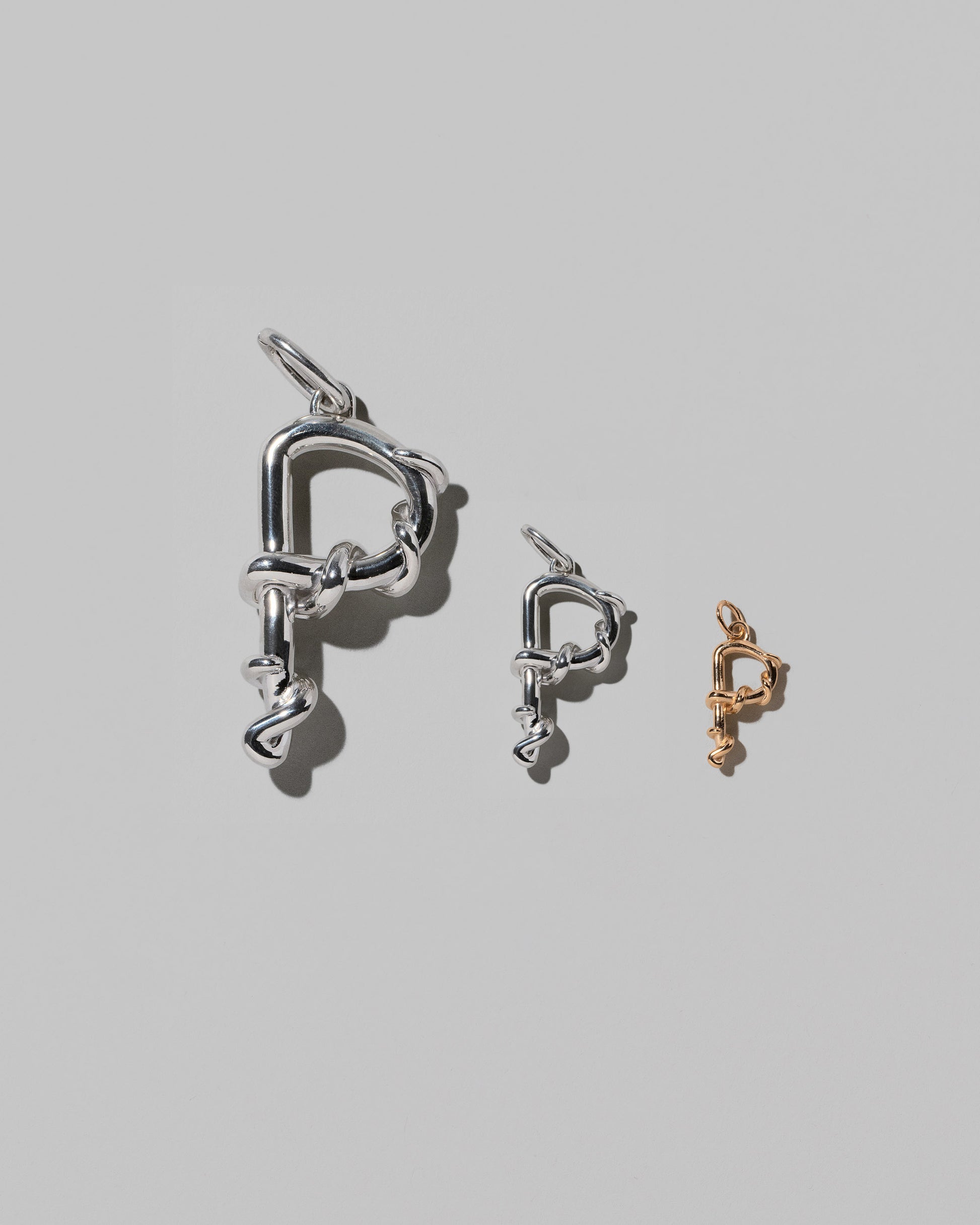 CRZM Large Sterling Silver, Medium Sterling Silver & Mini Letter P Charms set in solid gold on light color background.