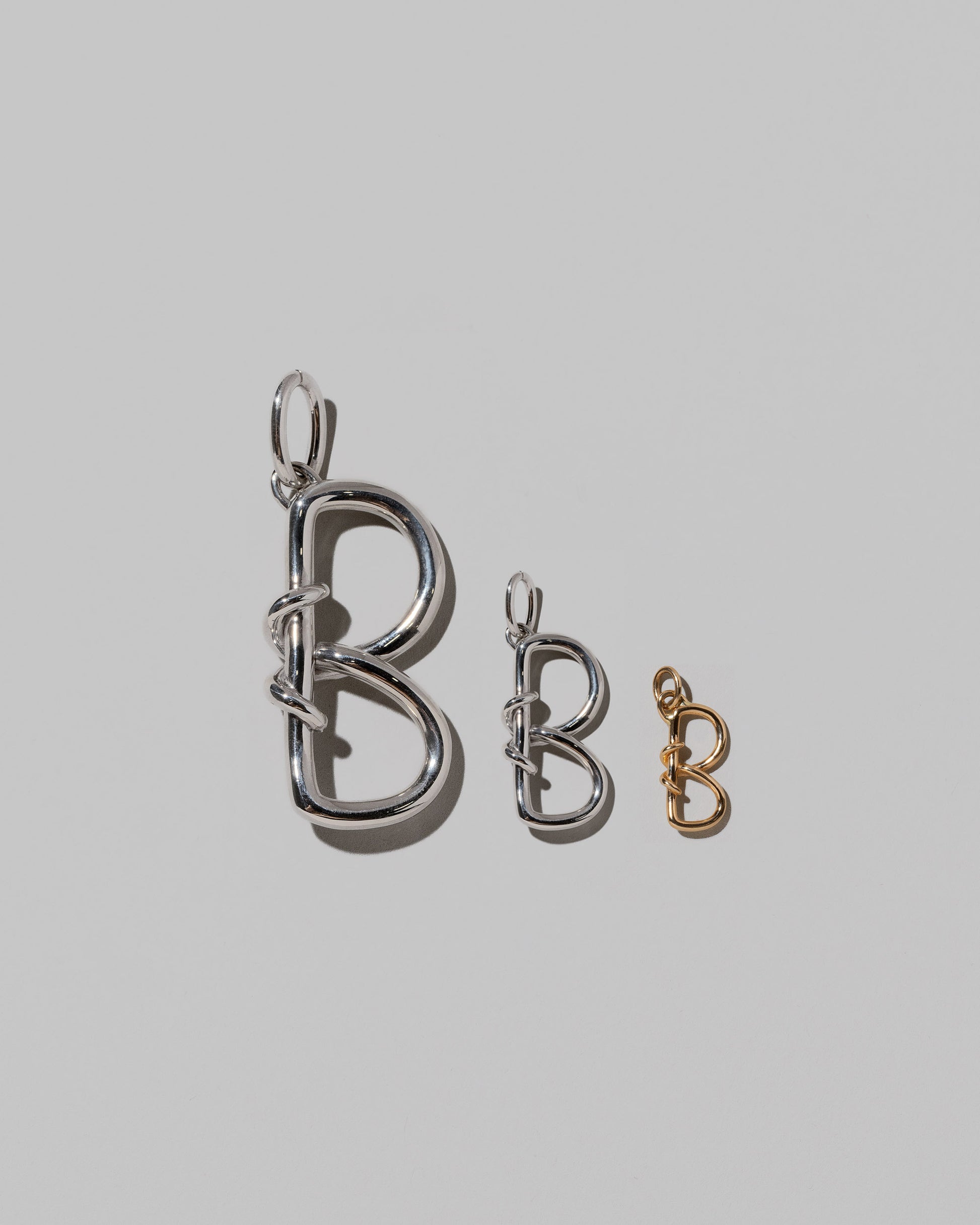 CRZM Large Sterling Silver, Medium Sterling Silver & Mini Letter B Charms set in solid gold on light color background.