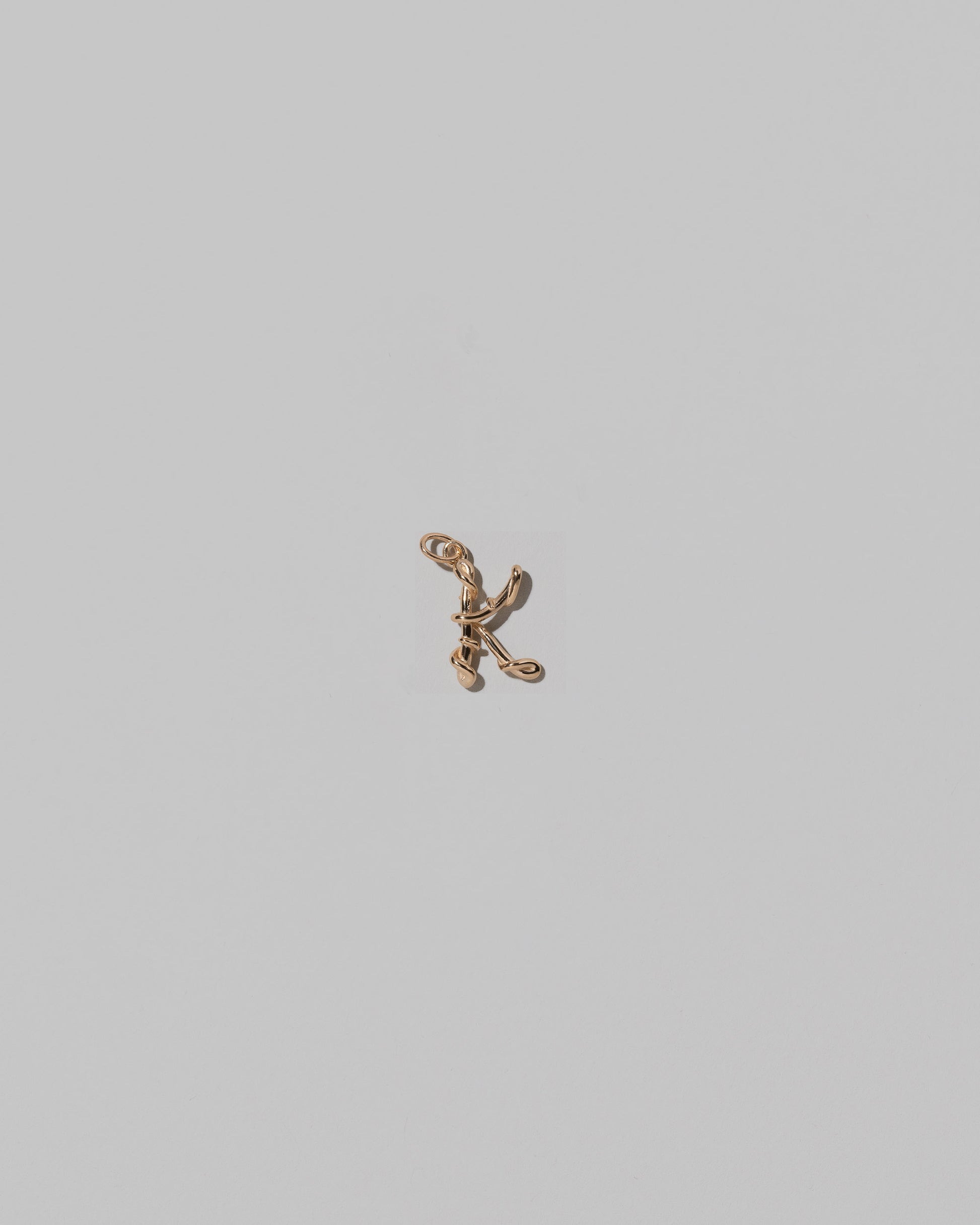 CRZM Mini Letter K set in solid gold on light color background.