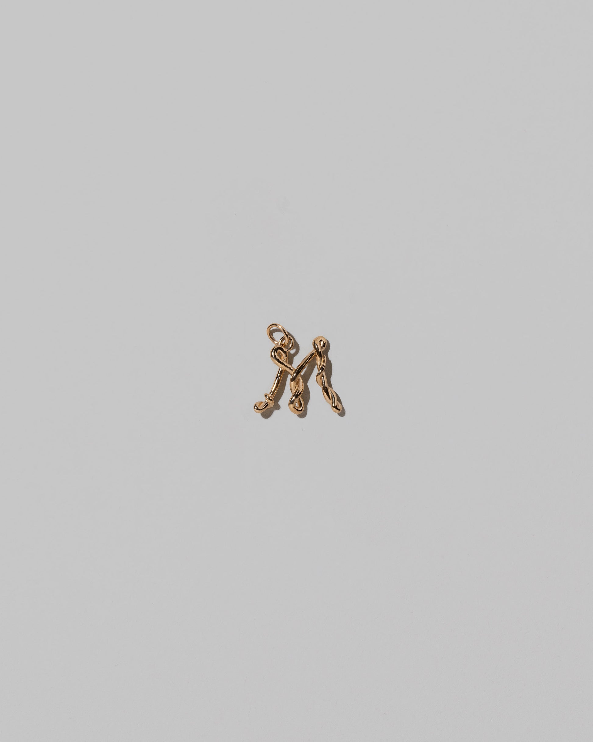 CRZM Mini Letter M set in solid gold on light color background.