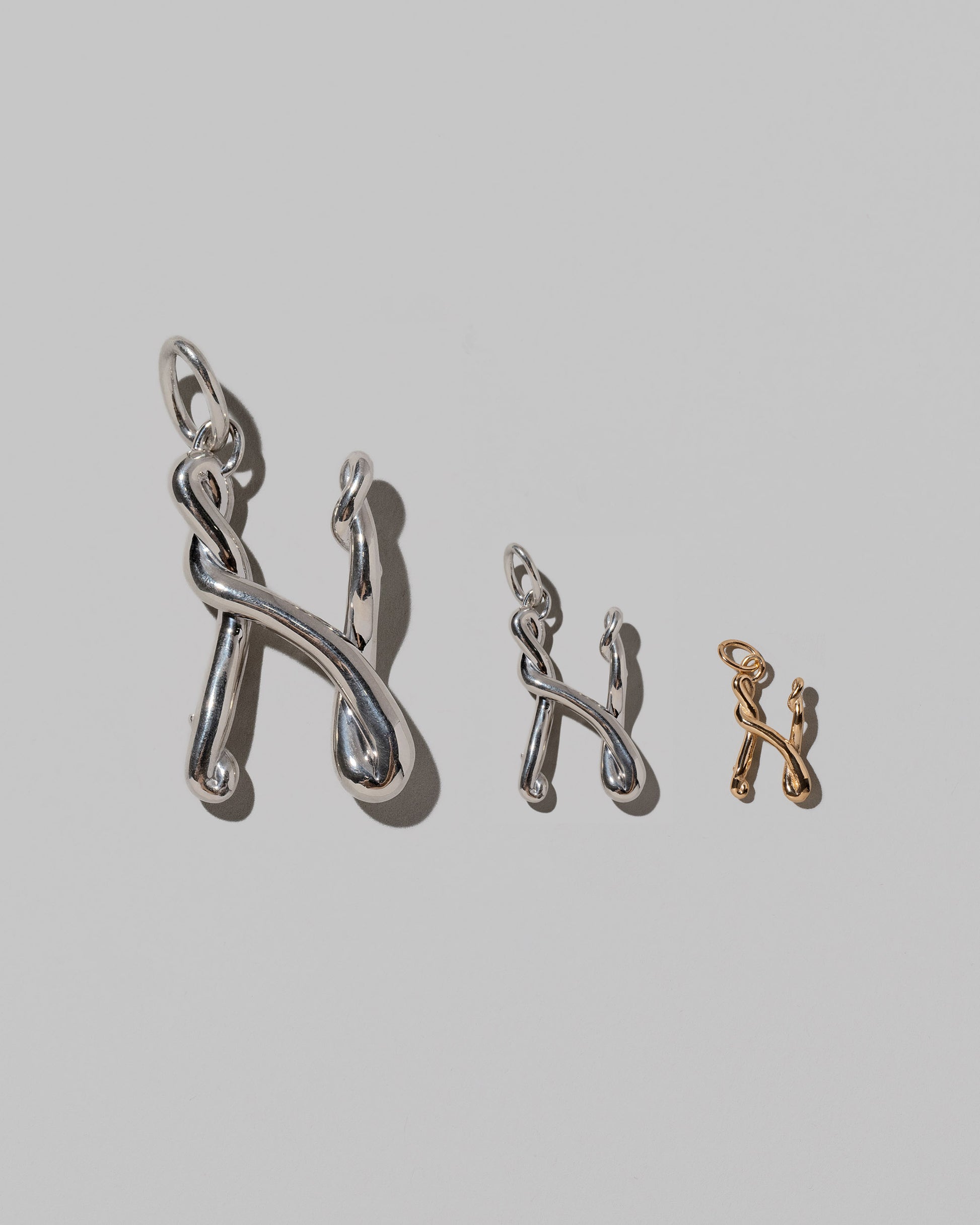 CRZM Large Sterling Silver, Medium Sterling Silver & Mini Letter N Charms set in solid gold on light color background.