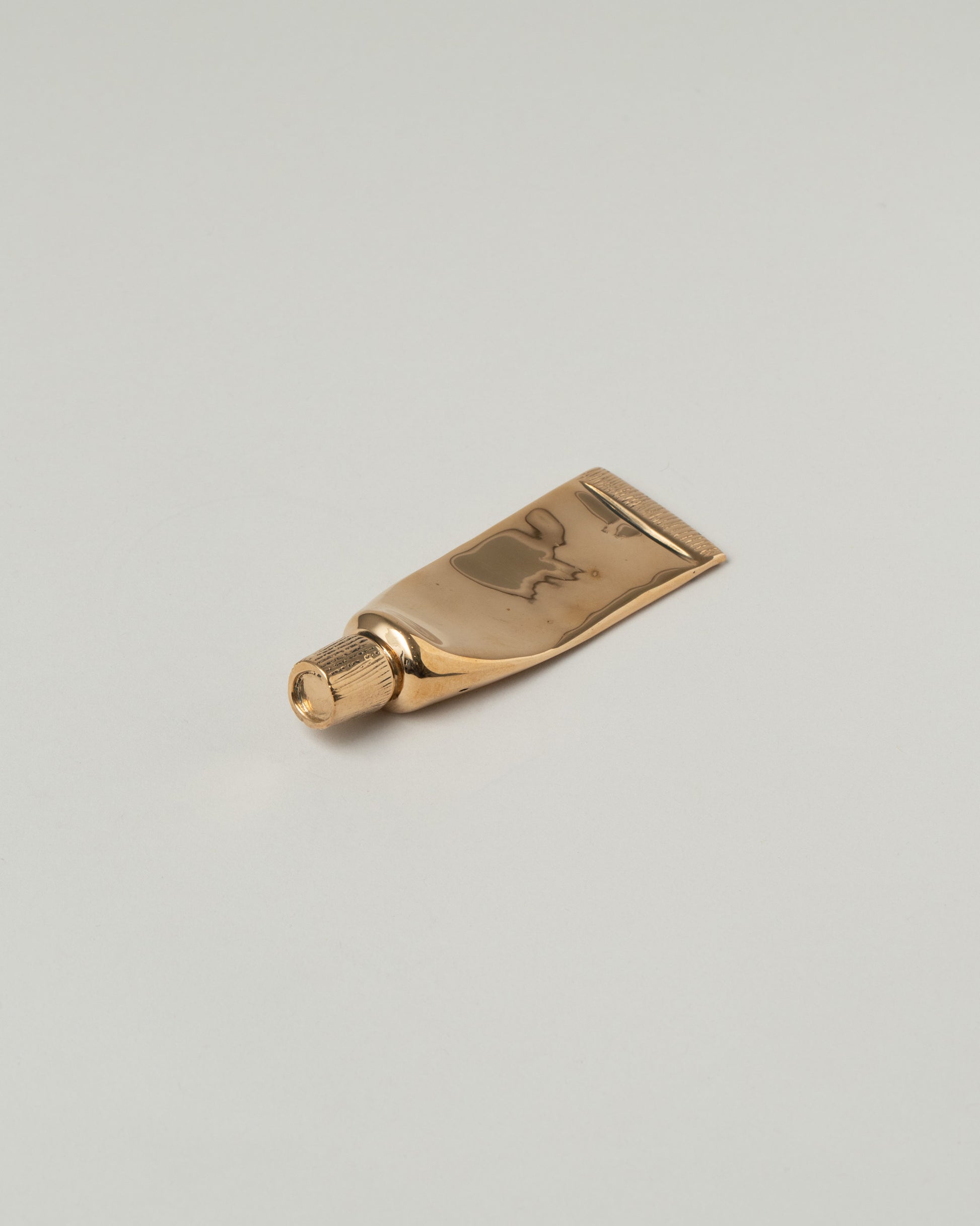 Pearce Objects Cast Bronze Travel-Sized Toothpaste Tube on light color background.