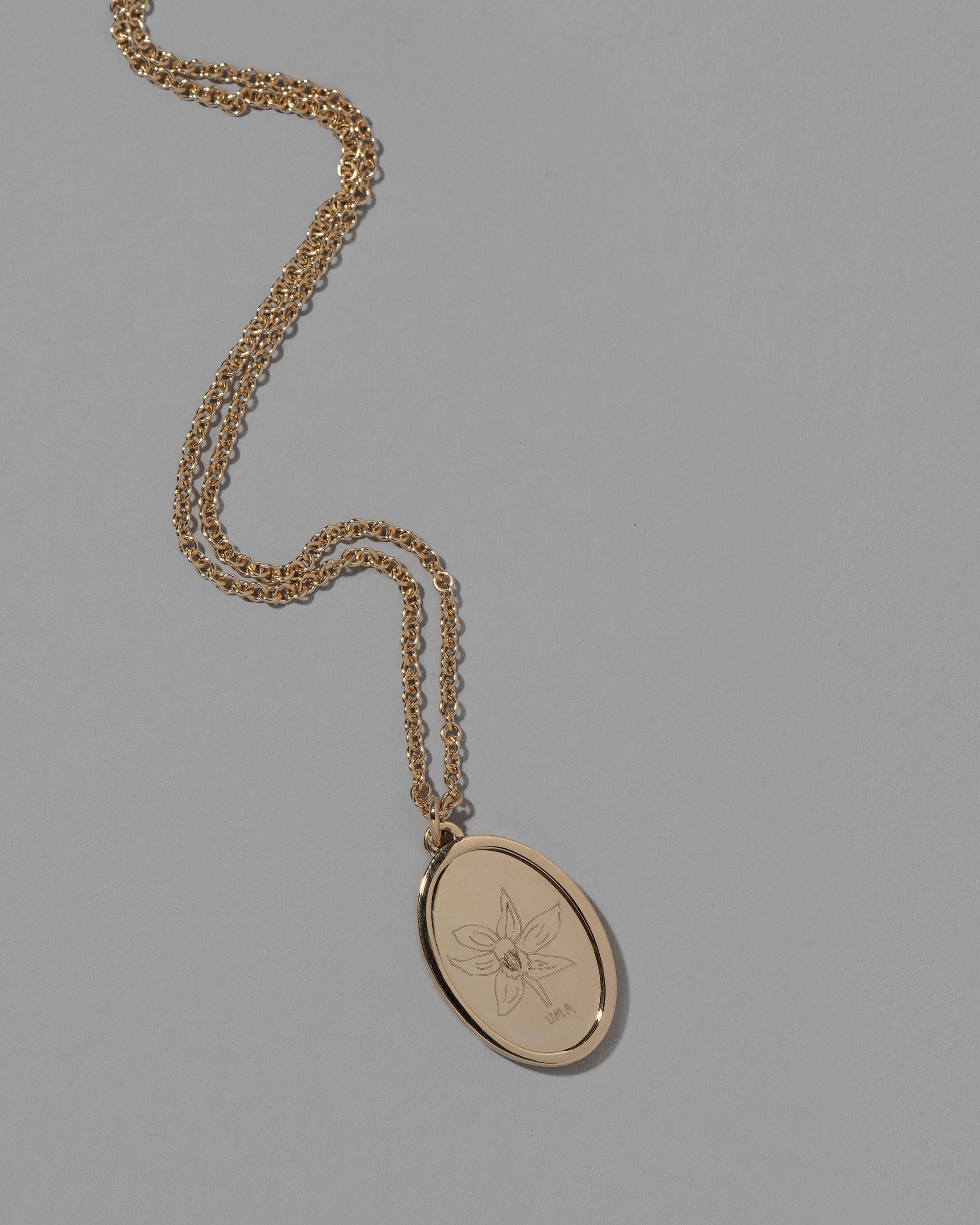 Closeup details of a finished Large Oval Memento Necklace on light color background.