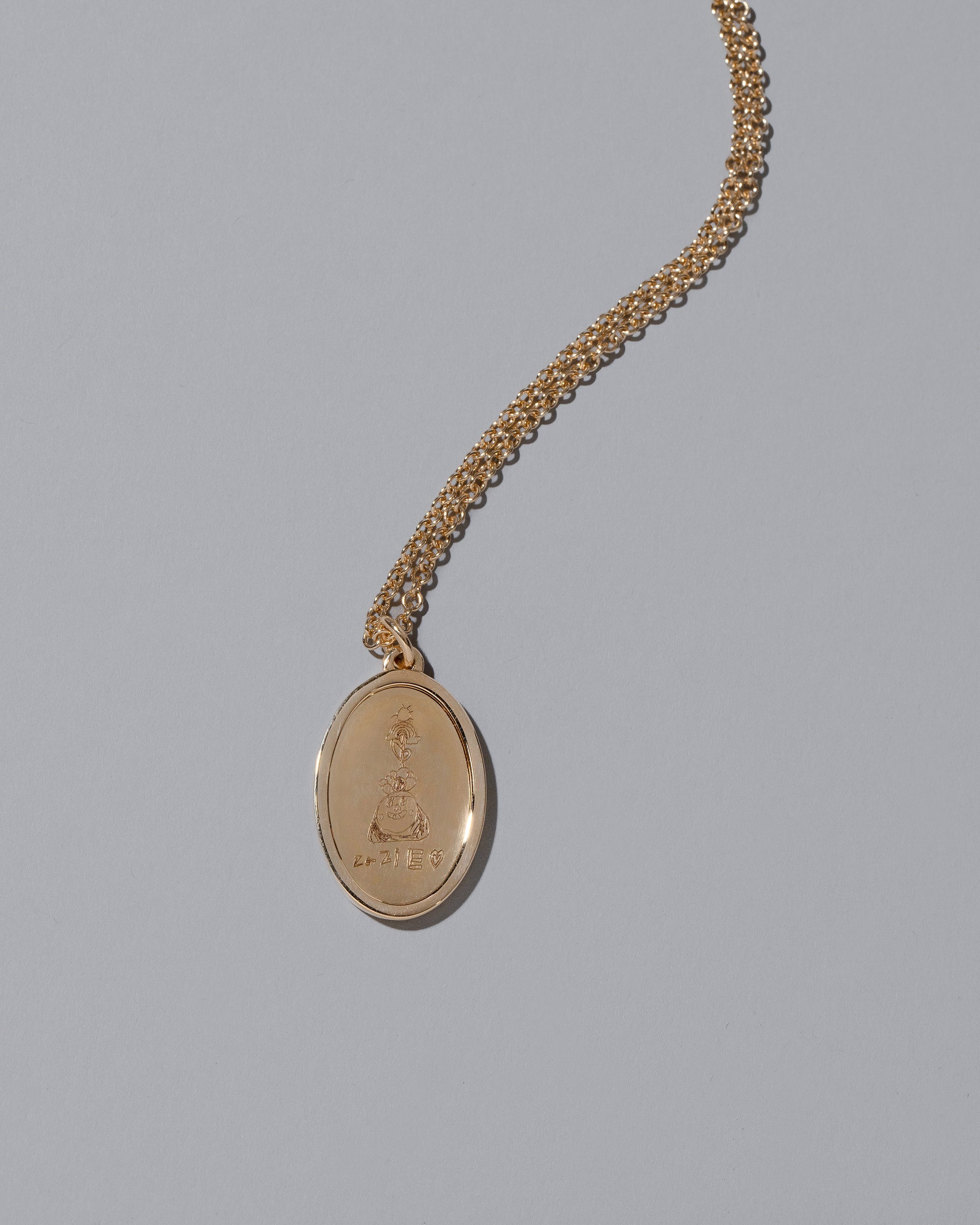 Closeup details of a finished Large Oval Memento Necklace Side Two on light color background.