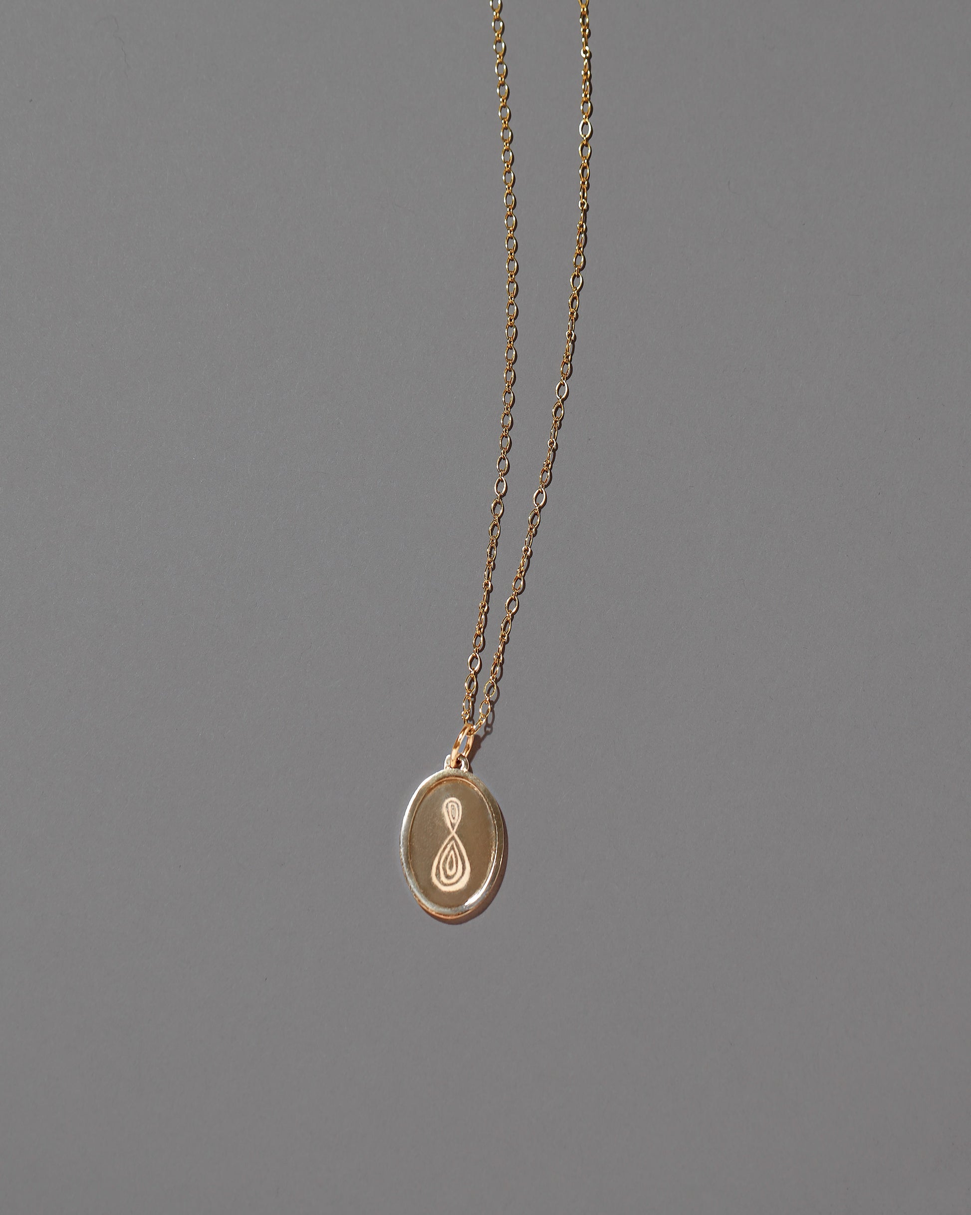 Finished Large Oval Memento Pendant on light color background, pictured with a Mociun Chain.