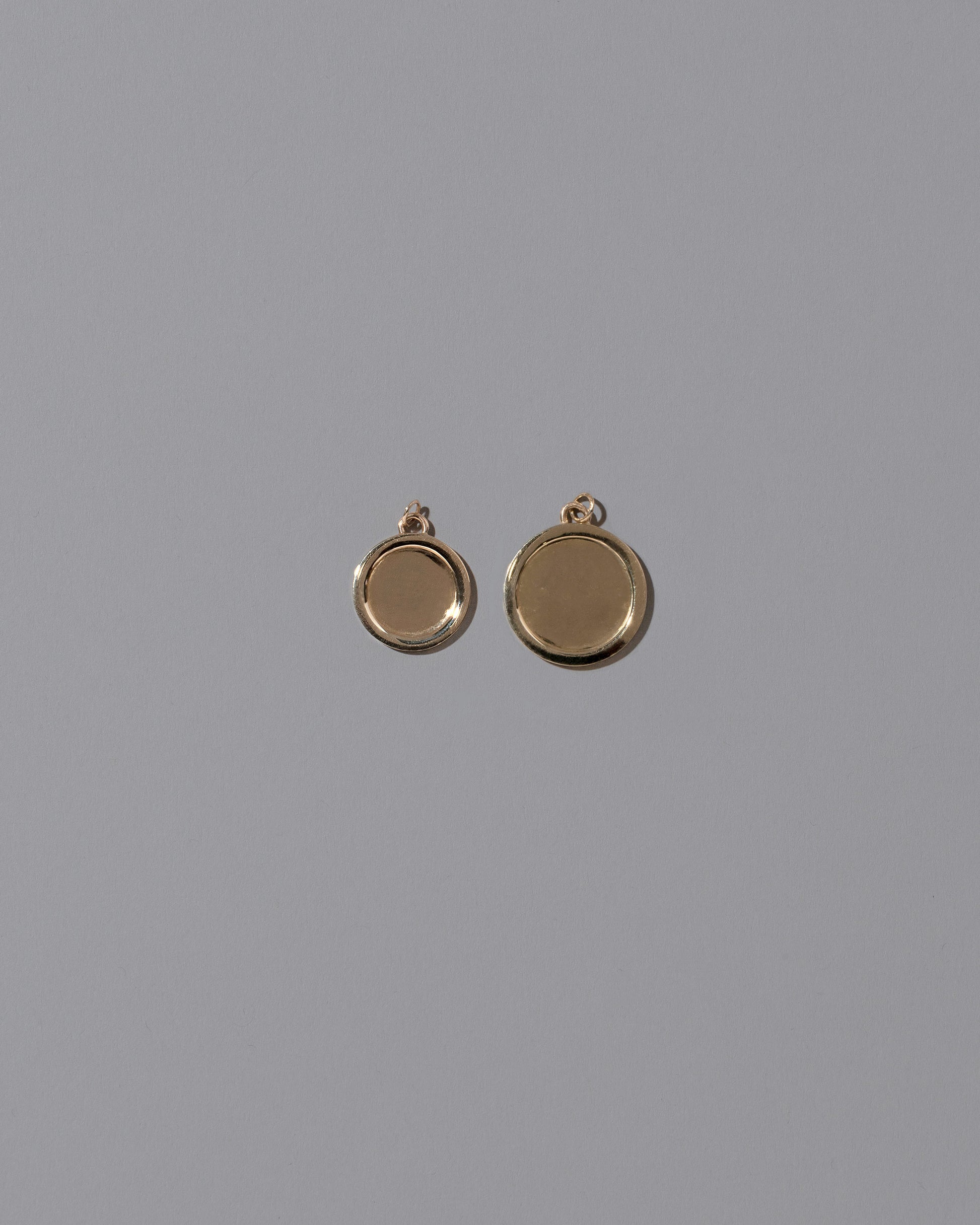 Group of unfinished Small and Large Round Memento Pendants on light color background.