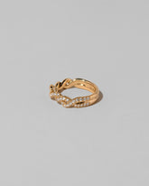 View from the side of the Gold Pavé Twist Band on light color background.