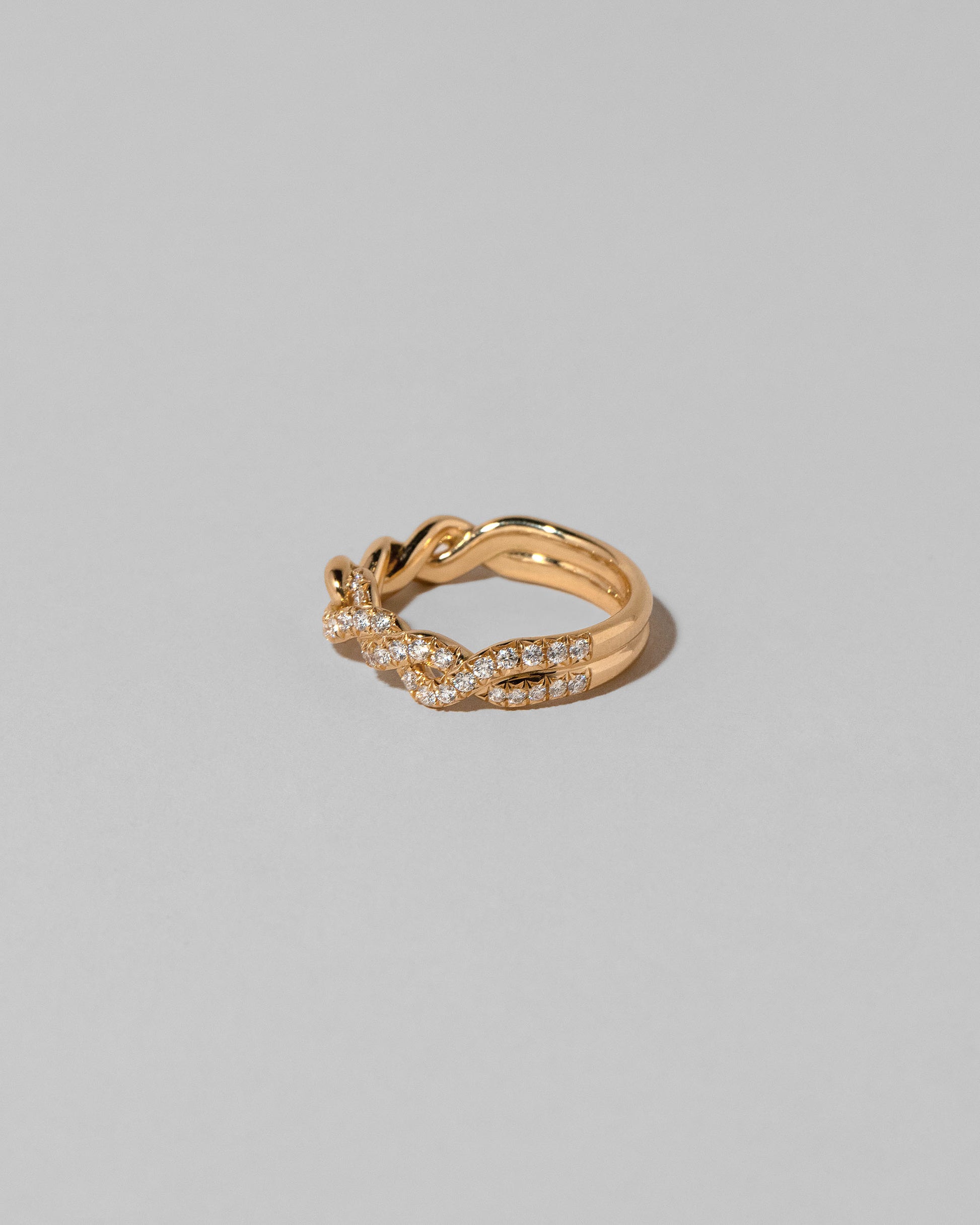 View from the side of the Gold Pavé Twist Band on light color background.