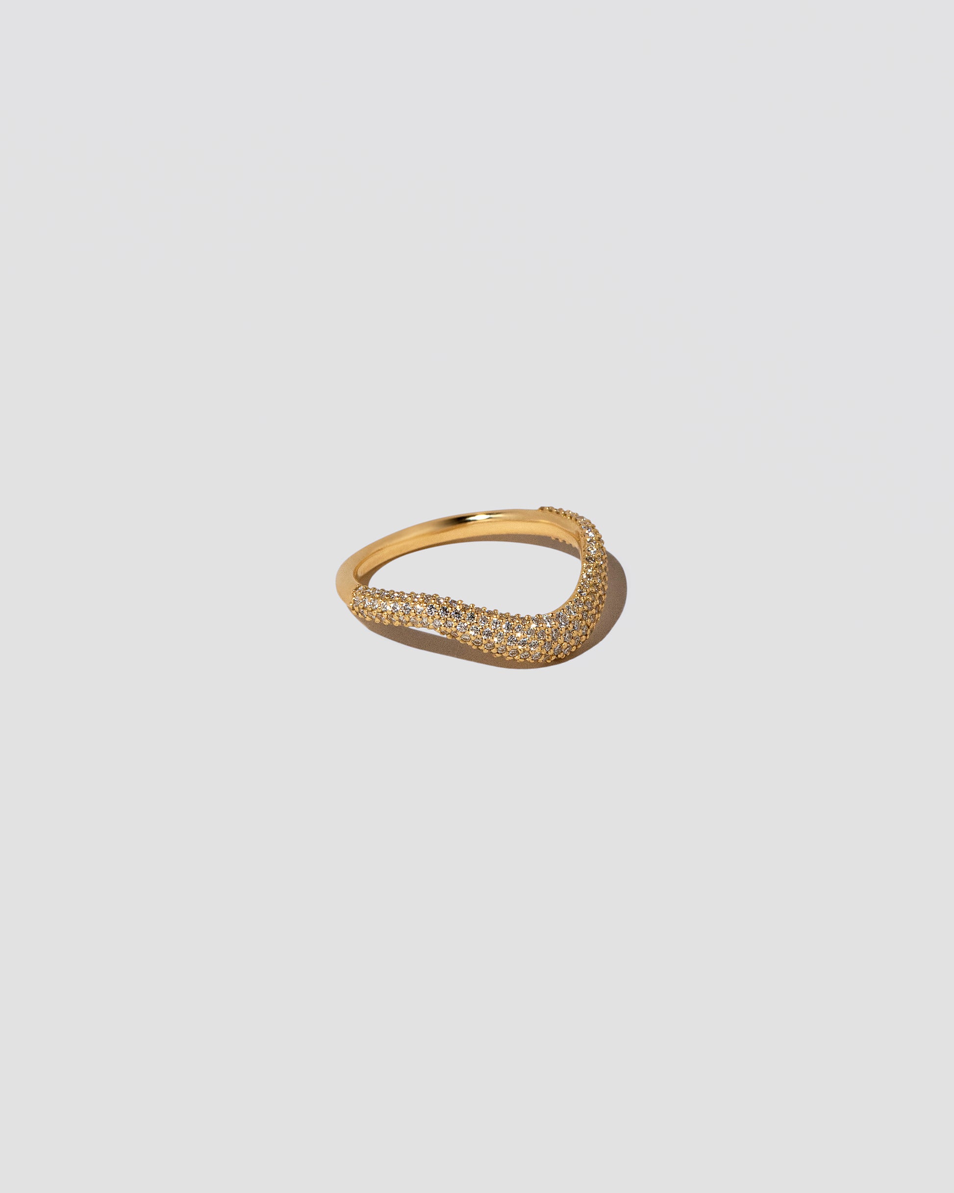 View from the side of the Gold Pavé Thin Level Band on light color background.