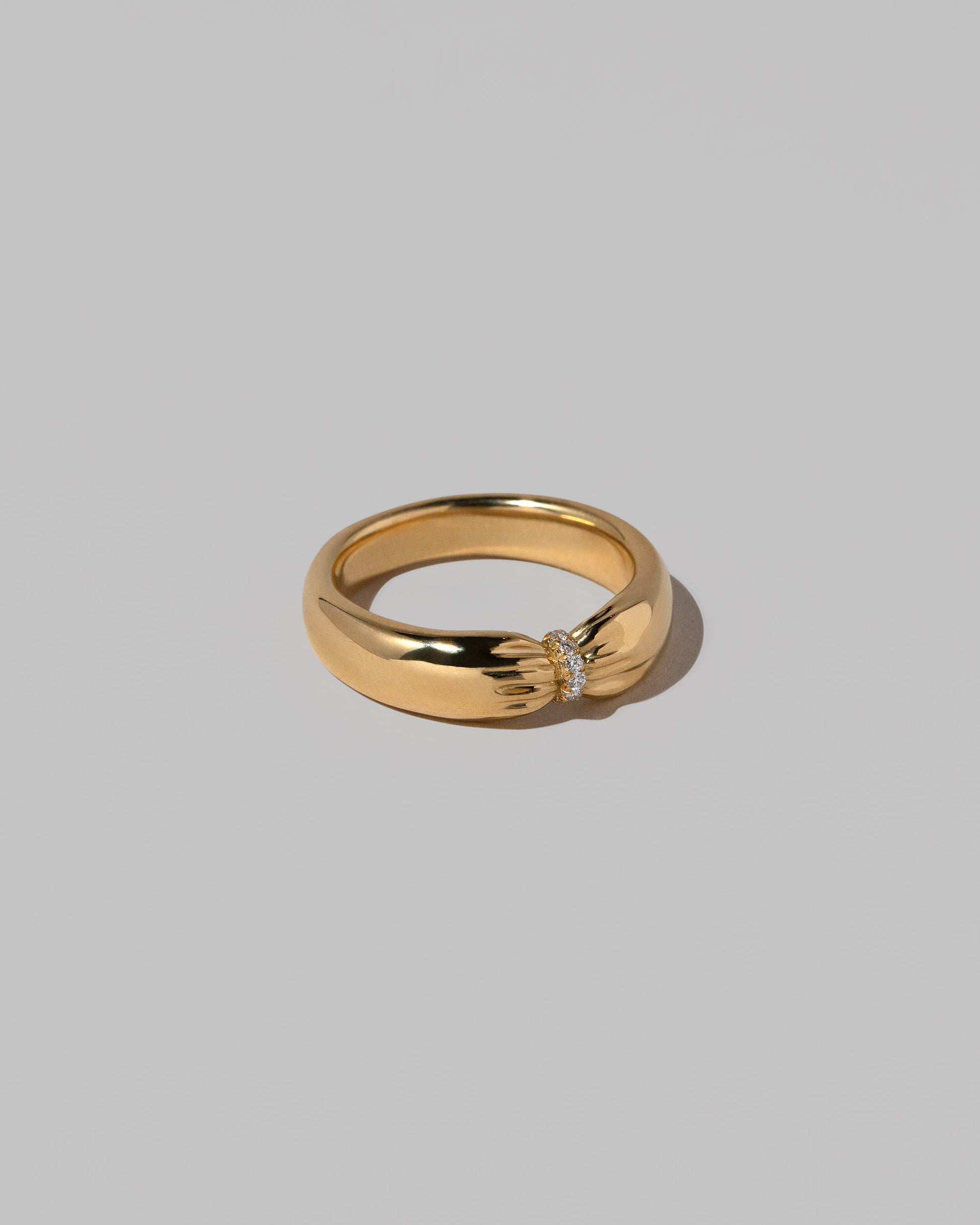 View from the side of the Gold Pavé Pinch Band on light color background.